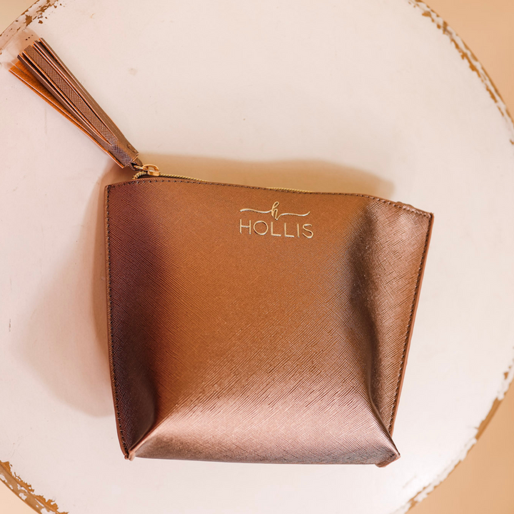 A mocha metallic bag is laid in the center of the picture. Background is solid white. 