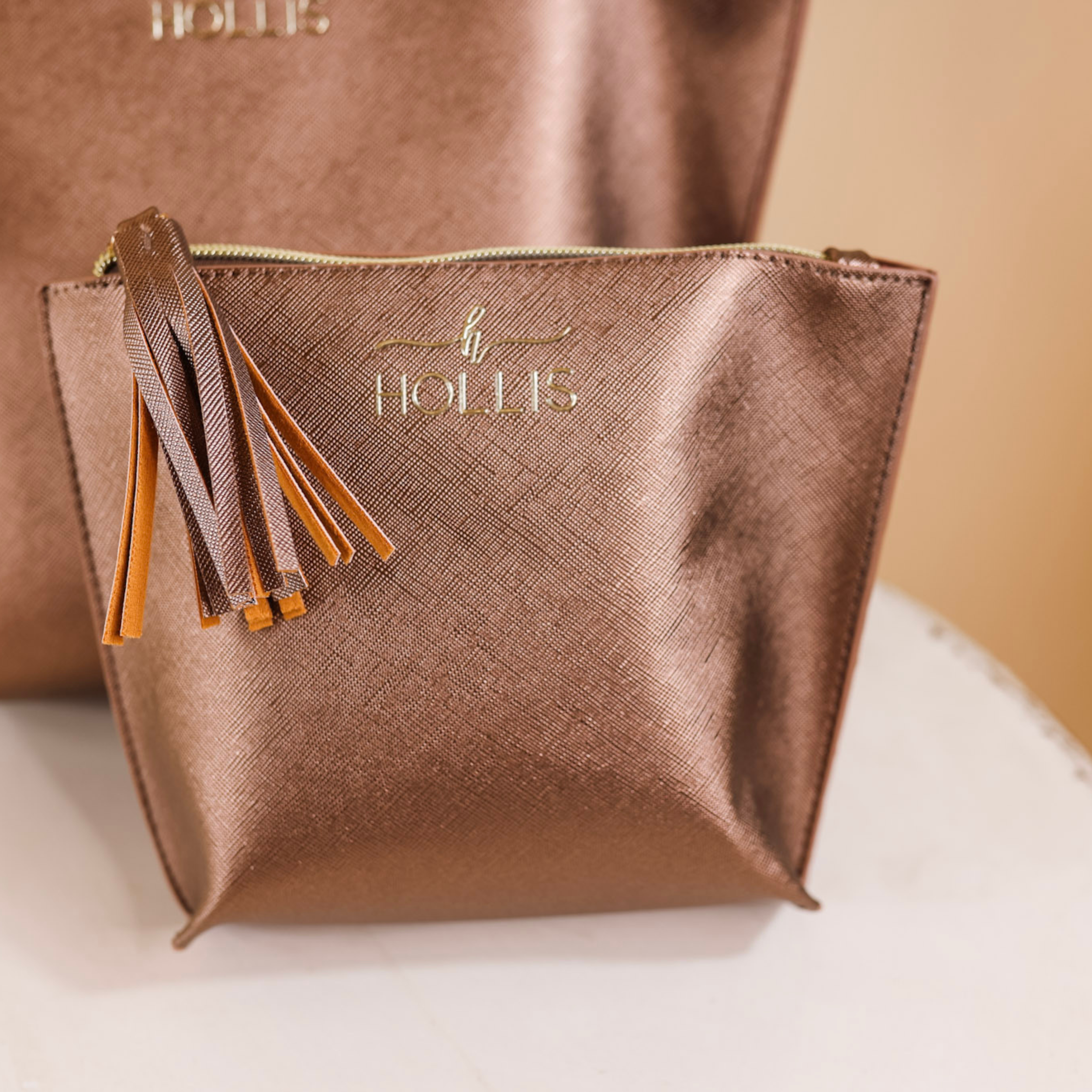 A mocha metallic bag is laid in the center of the picture. Background is solid white.