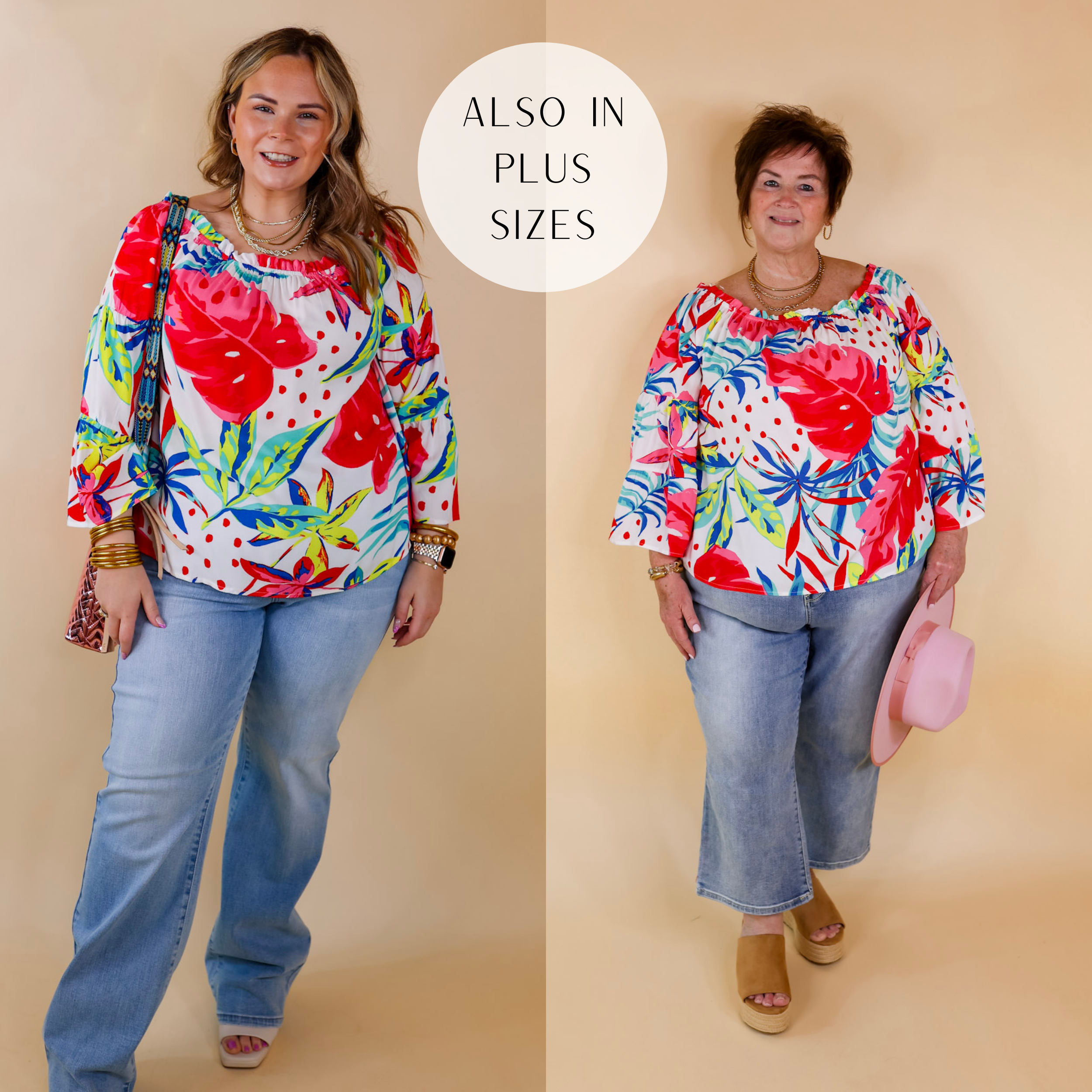 Model is wearing an off the shoulder blouse with a red, pink, blue, and green floral print. Model has this top paired with wide leg jeans, white heels, a pink purse, and gold jewelry.
