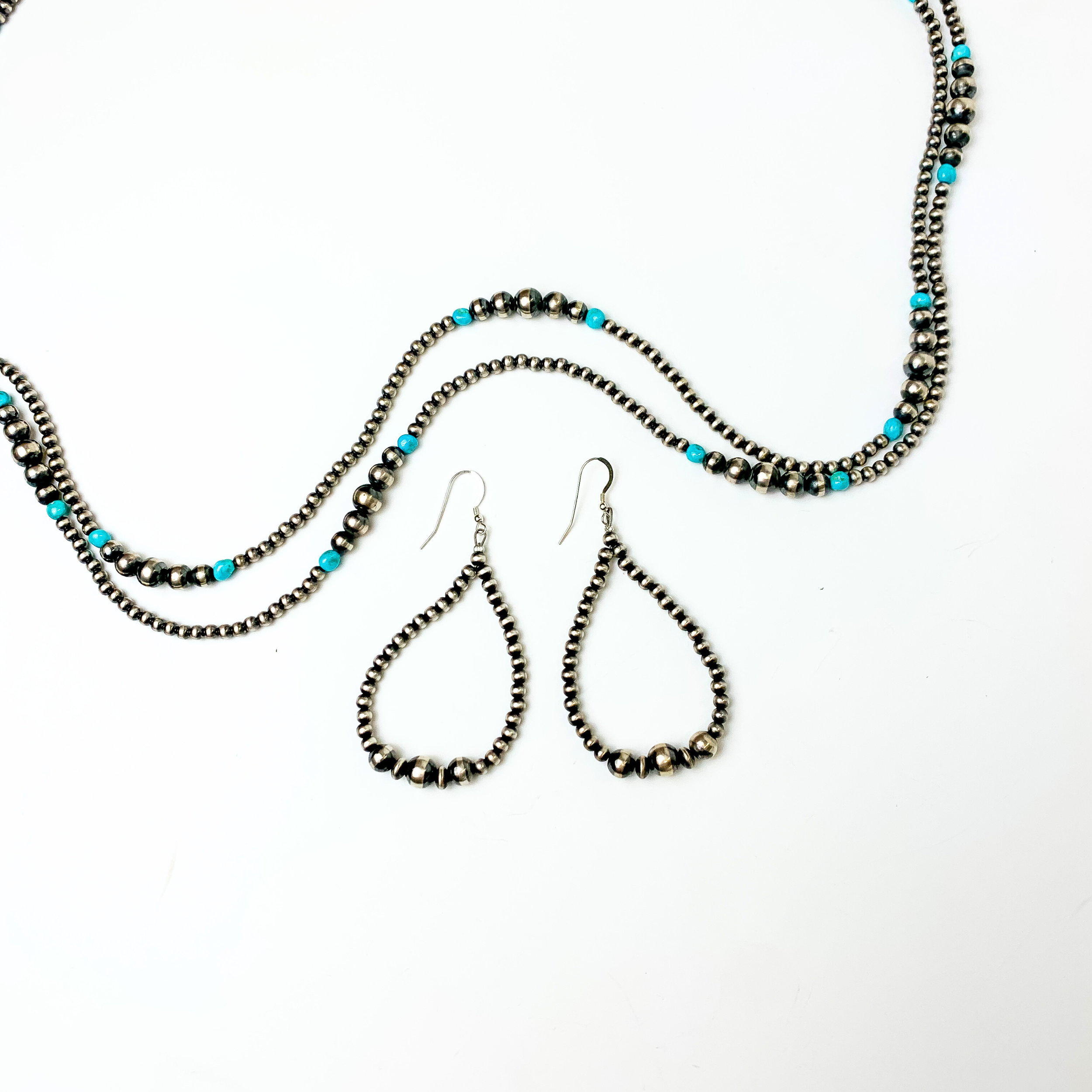 Centered in the picture is a pair of navajo pearl teardrop earrings on a white background. 
