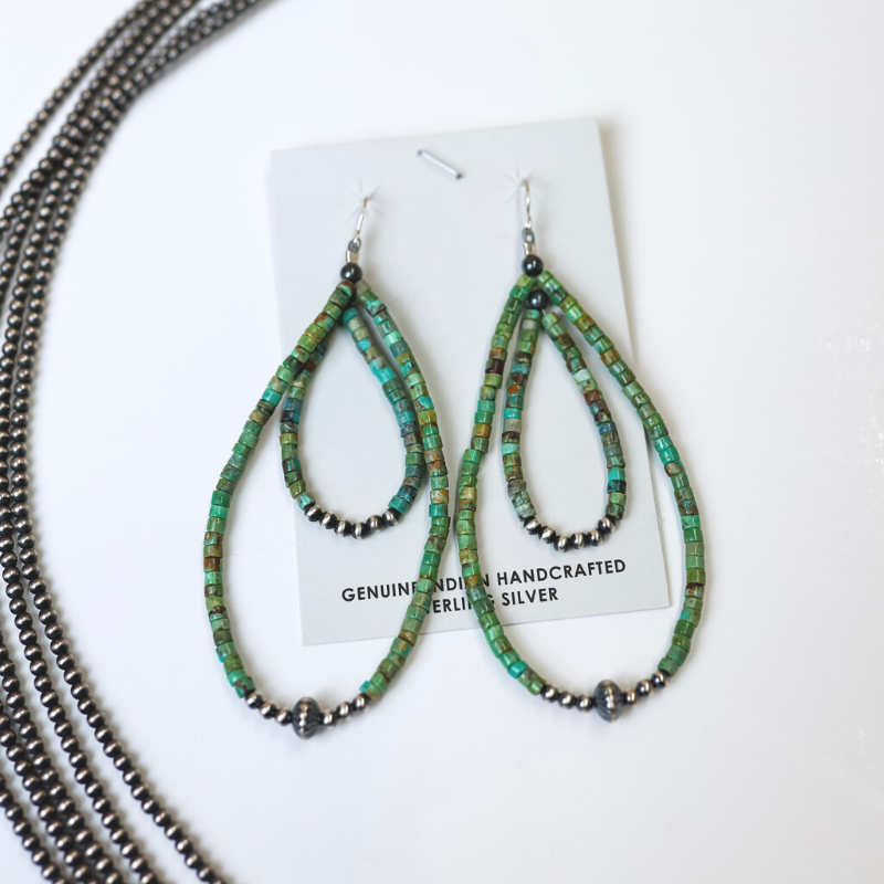 Navajo Handmade Double Layered Turquoise Beaded Teardrop Earrings with Sterling Silver Navajo Pearls are centered in the picture, with navajo pearls are laid to the left of the earrings. All background is white. 