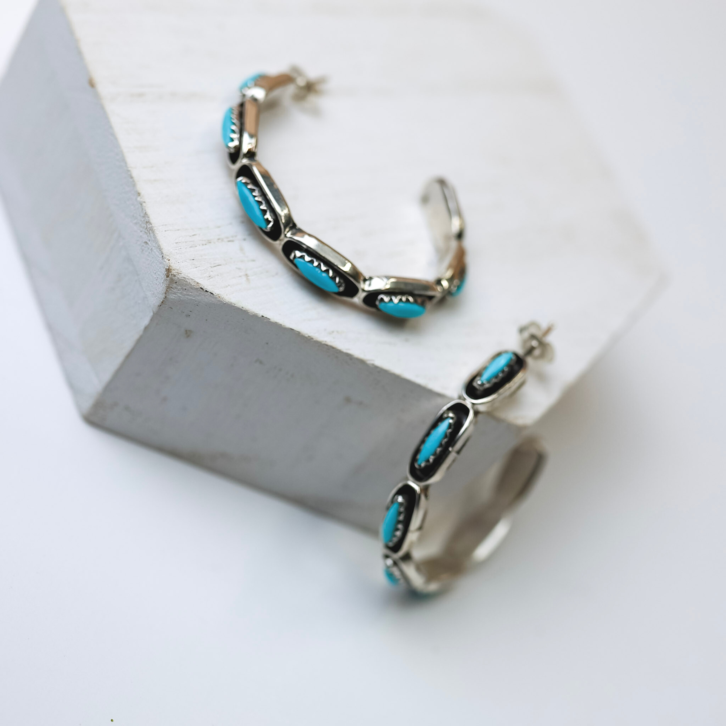 Navajo Handmade Genuine Sterling Silver Hoops with Turquoise Stones are centered in the picture. All background is white. 