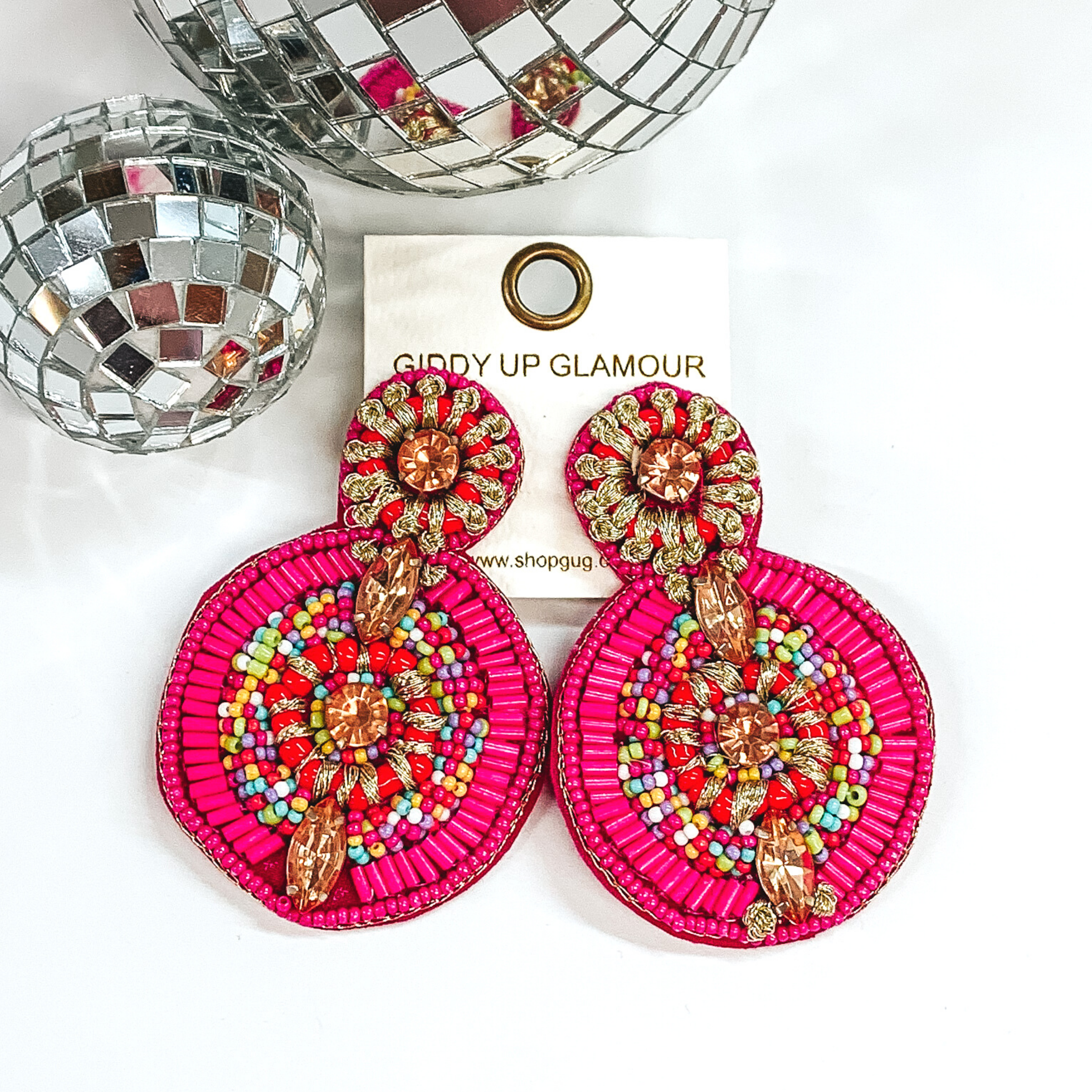 A small circle connected to a bigger circle and the bottom. These earrings have fuchsia and multicolored beaded design. There is also some gold stitched designs and champagne crystal beads throughout. 