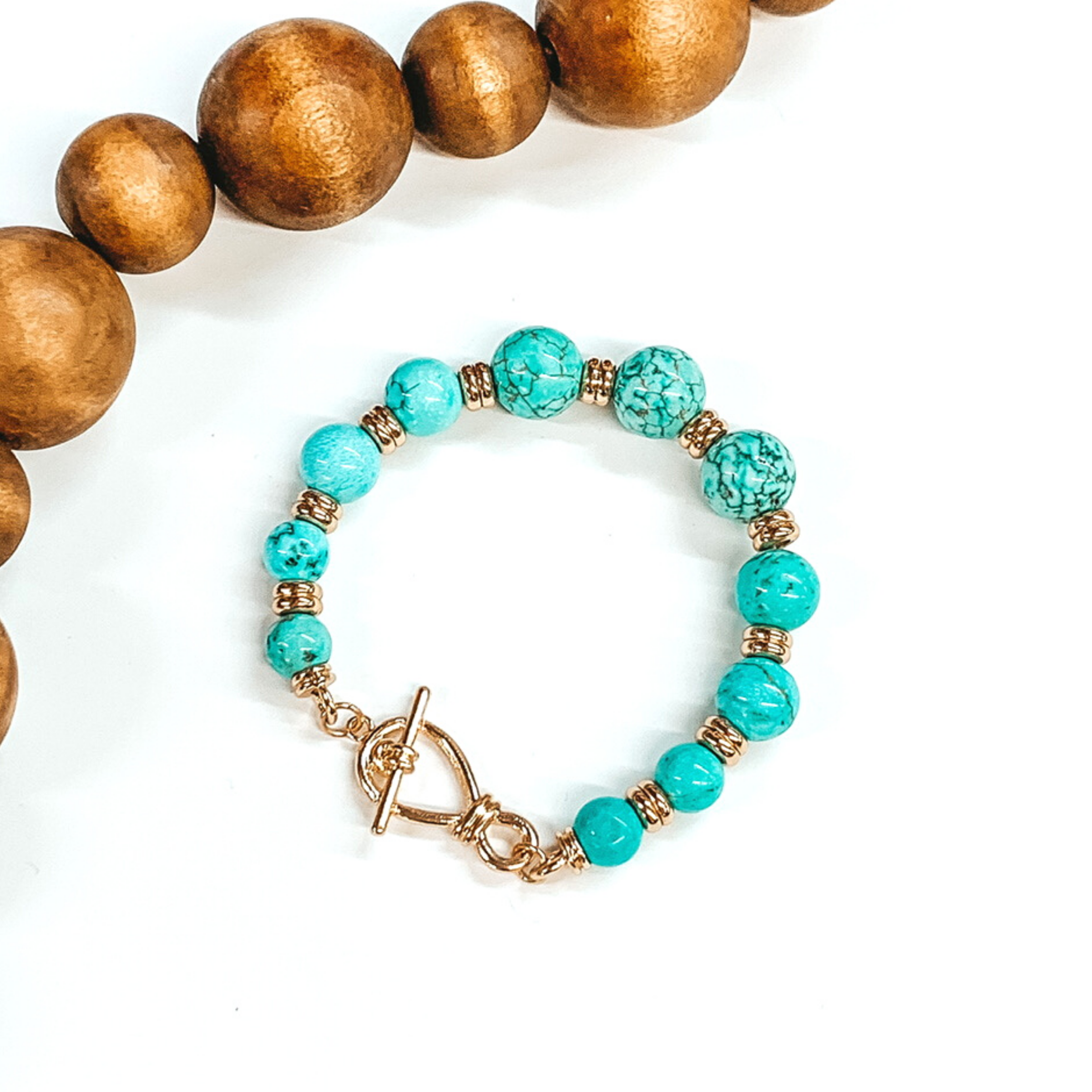 Turquoise and gold beaded bracelet with a frozen toggle clasp. This bracelet is pictured on a white background with dark brown beads at the top left corner. 