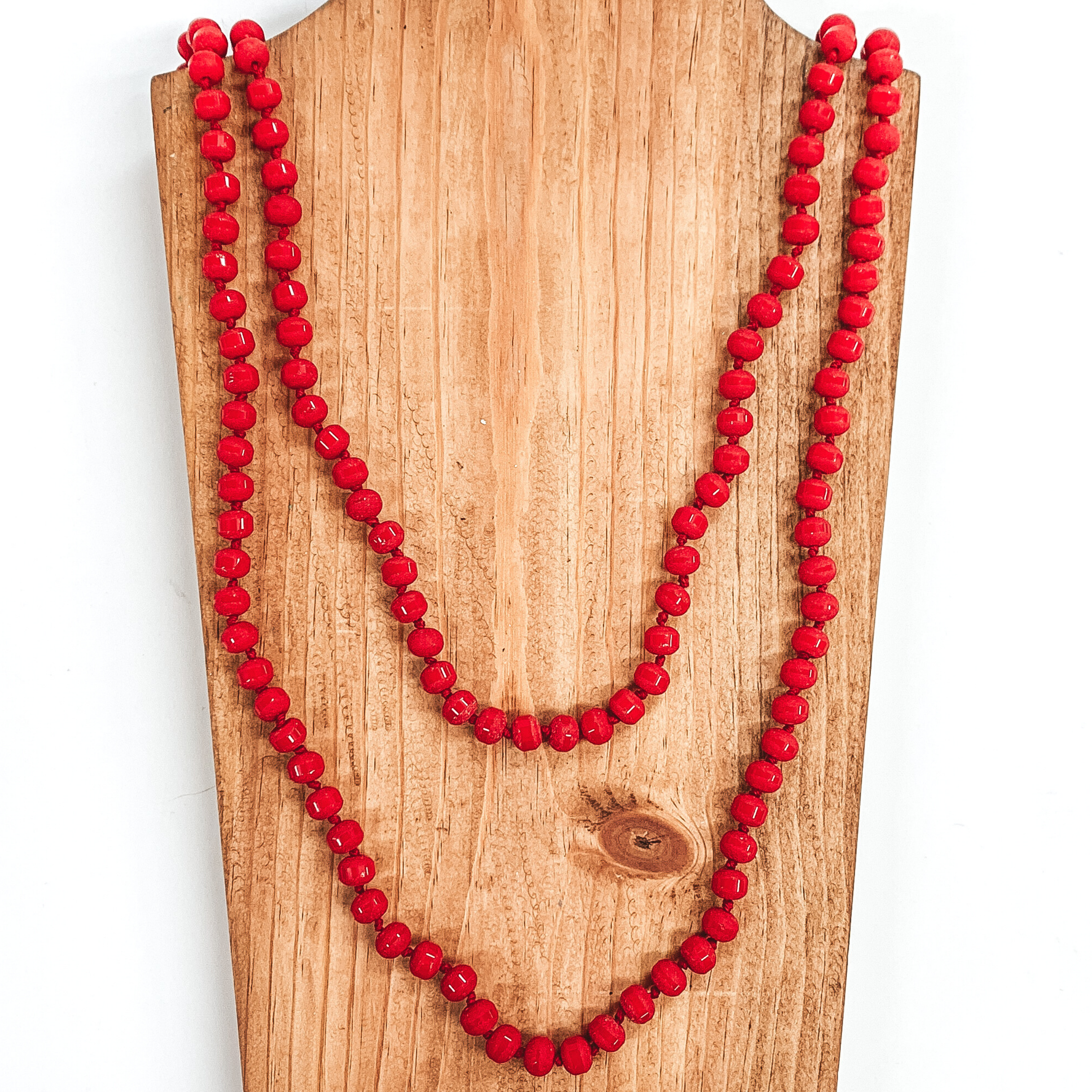 Crystal beaded necklace in druzy matte red. This necklace is pictured on a wooden necklace holder on a white background. 