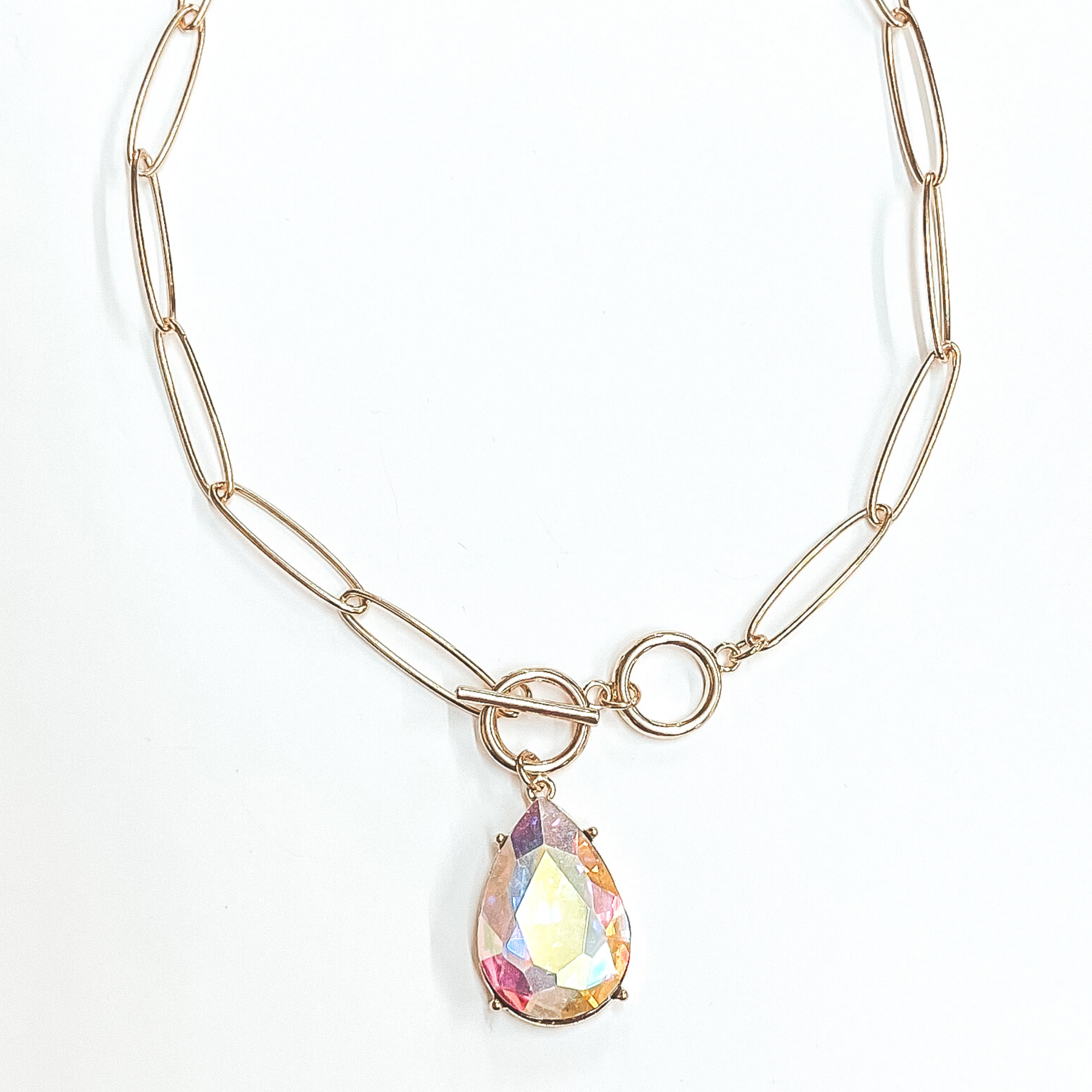 Gold, thin chain necklace with front toggle clasp. This necklace includes an AB teardrop crystal. This necklace is pictured on a white background. 