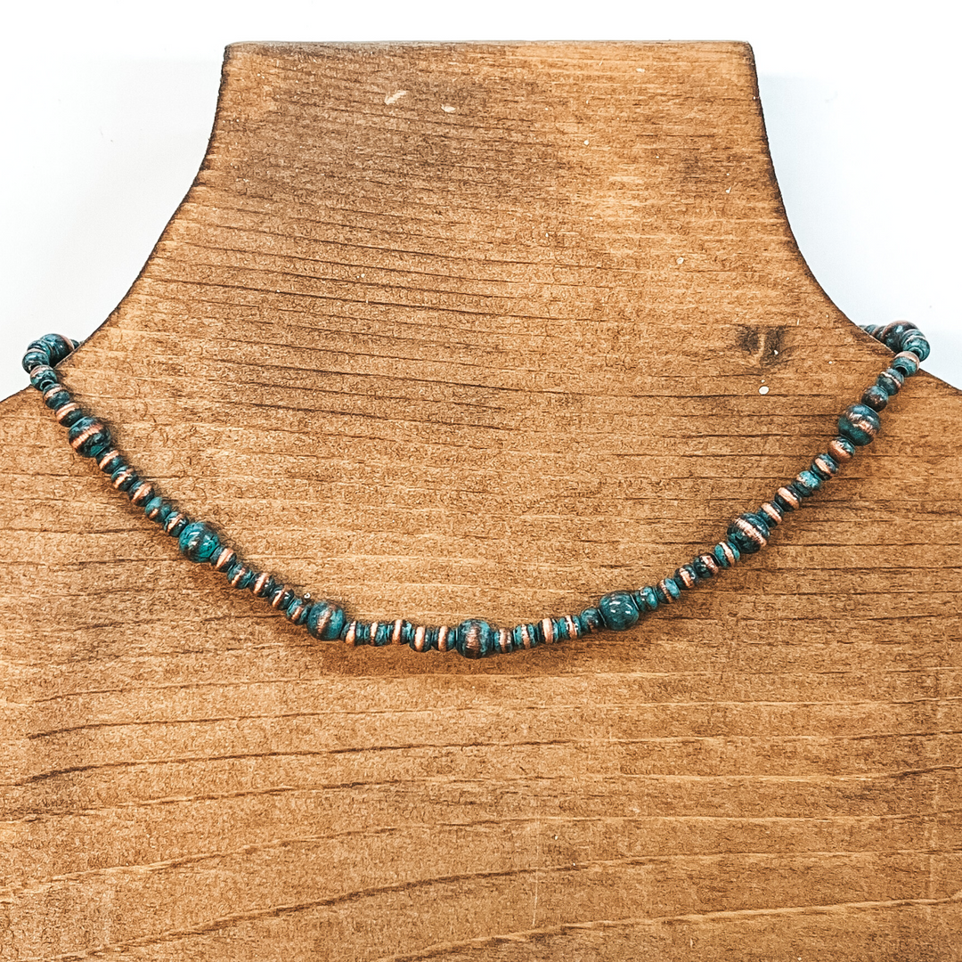 Patina beaded necklace with spacers in a larger size. This necklace is pictured on a brown necklace holder on a white background.