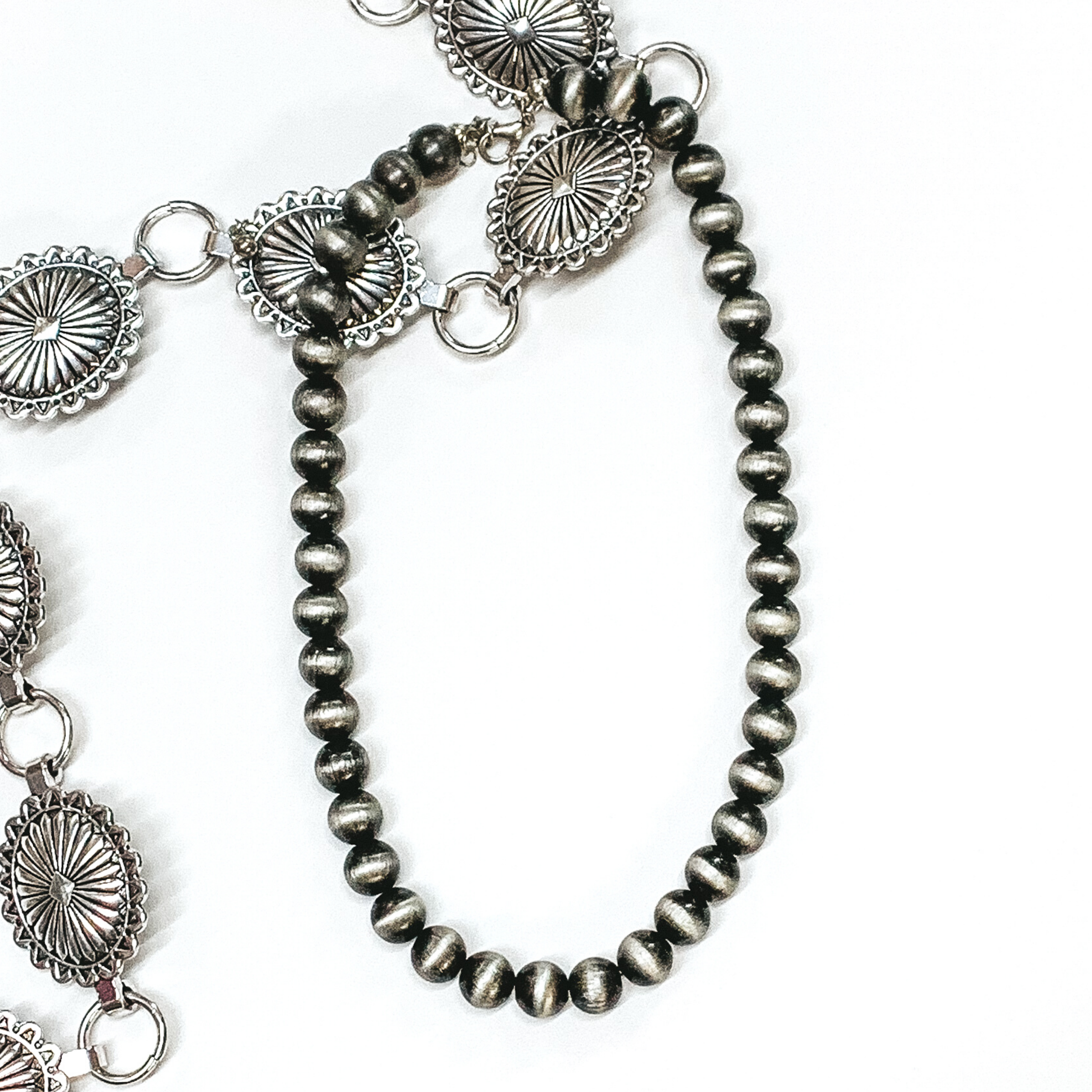 Silver beaded necklace pictured on a white background with silver conchos as decoration.  