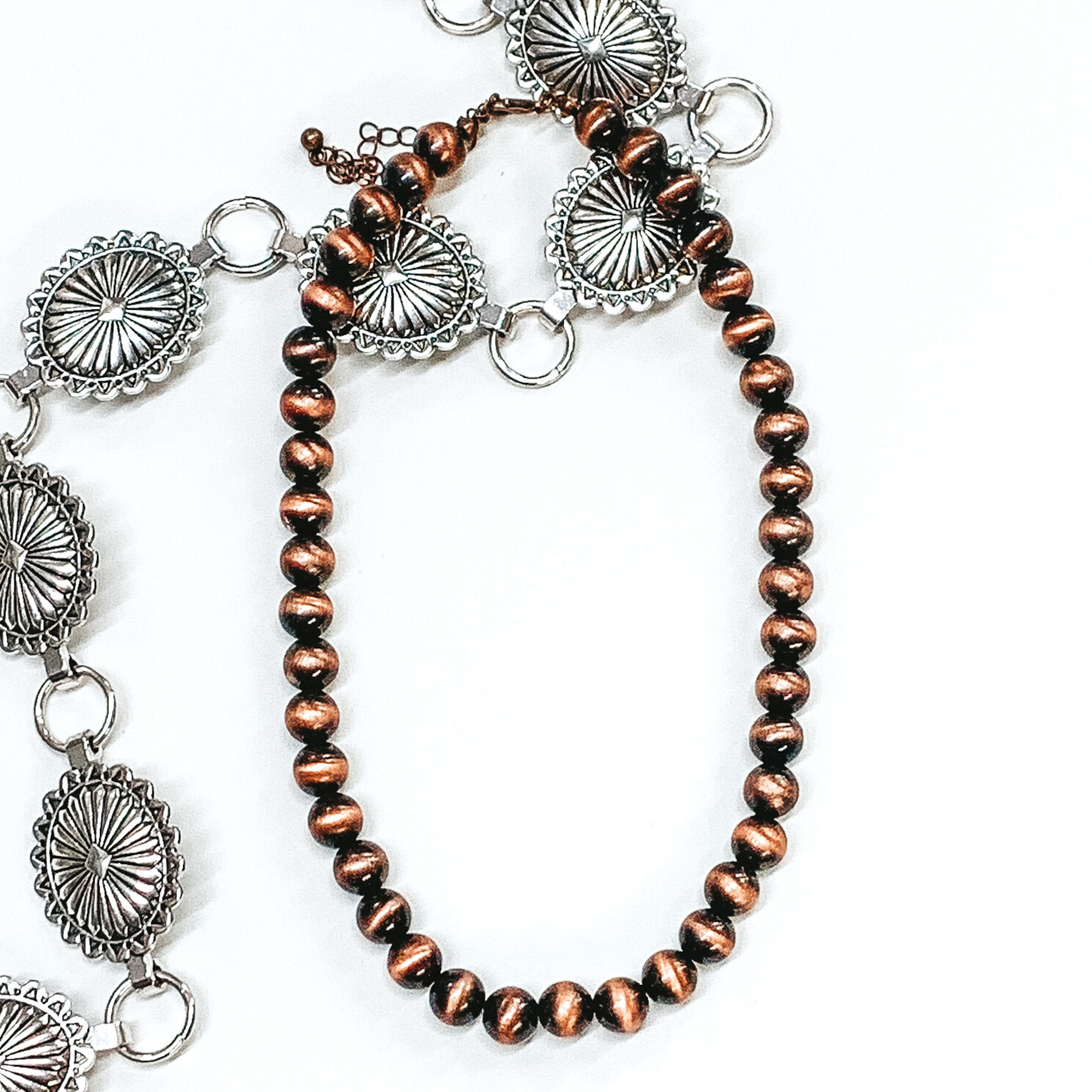 Copper beaded necklace pictured on a white background with silver conchos as decoration.