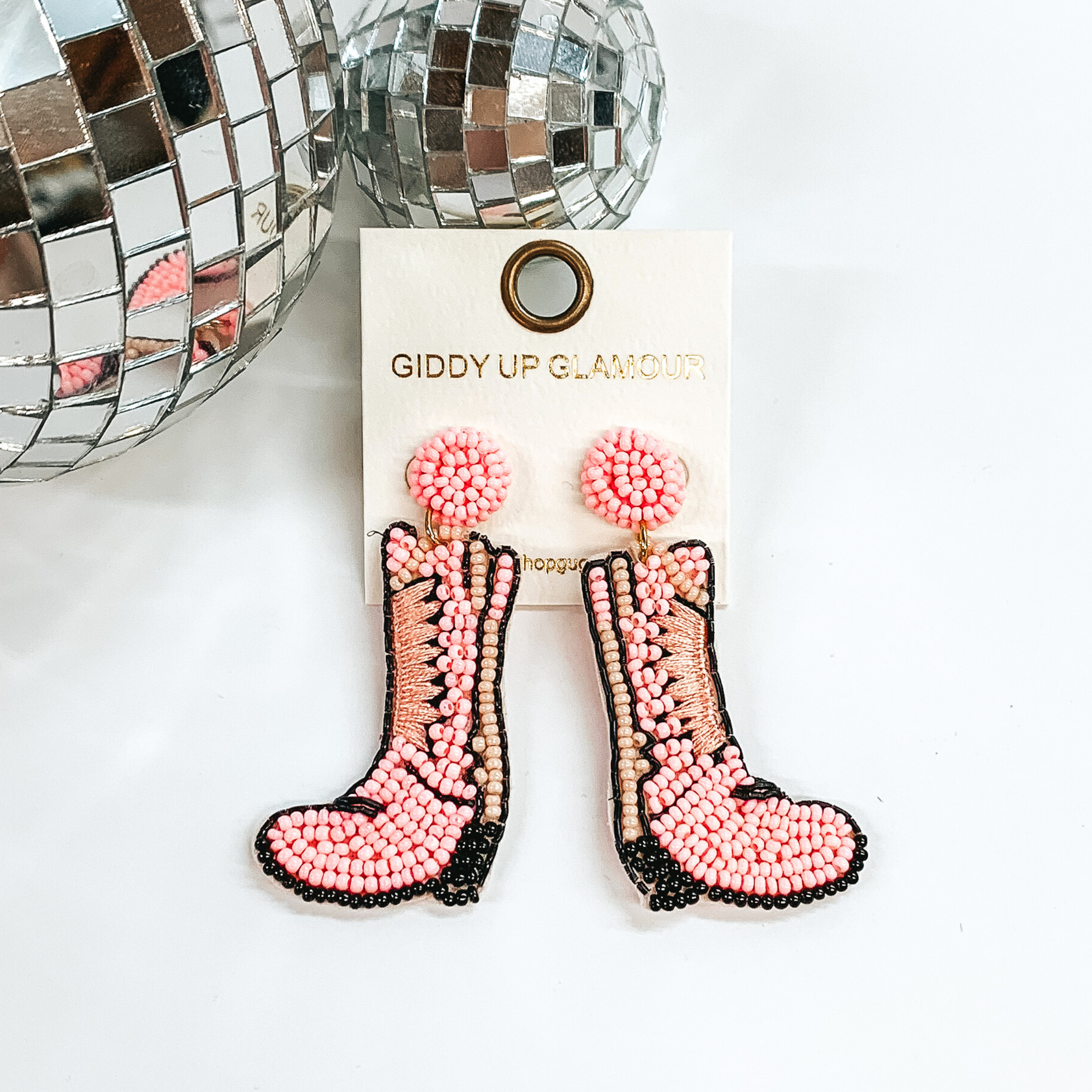 Beaded light pink boot post back earrings. These earrings include black and pink detailing. These earrings are pictured on a white background with disco balls in the top left corner.