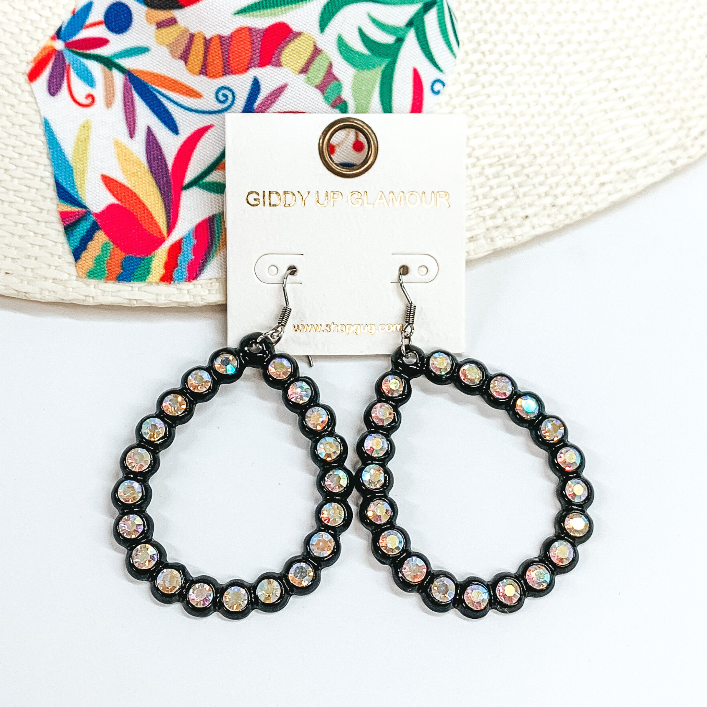 Black, open teardrop earrings with ab crystal outline. These earrings are pictured on a white background with a colorful piece of fabric behind them.
