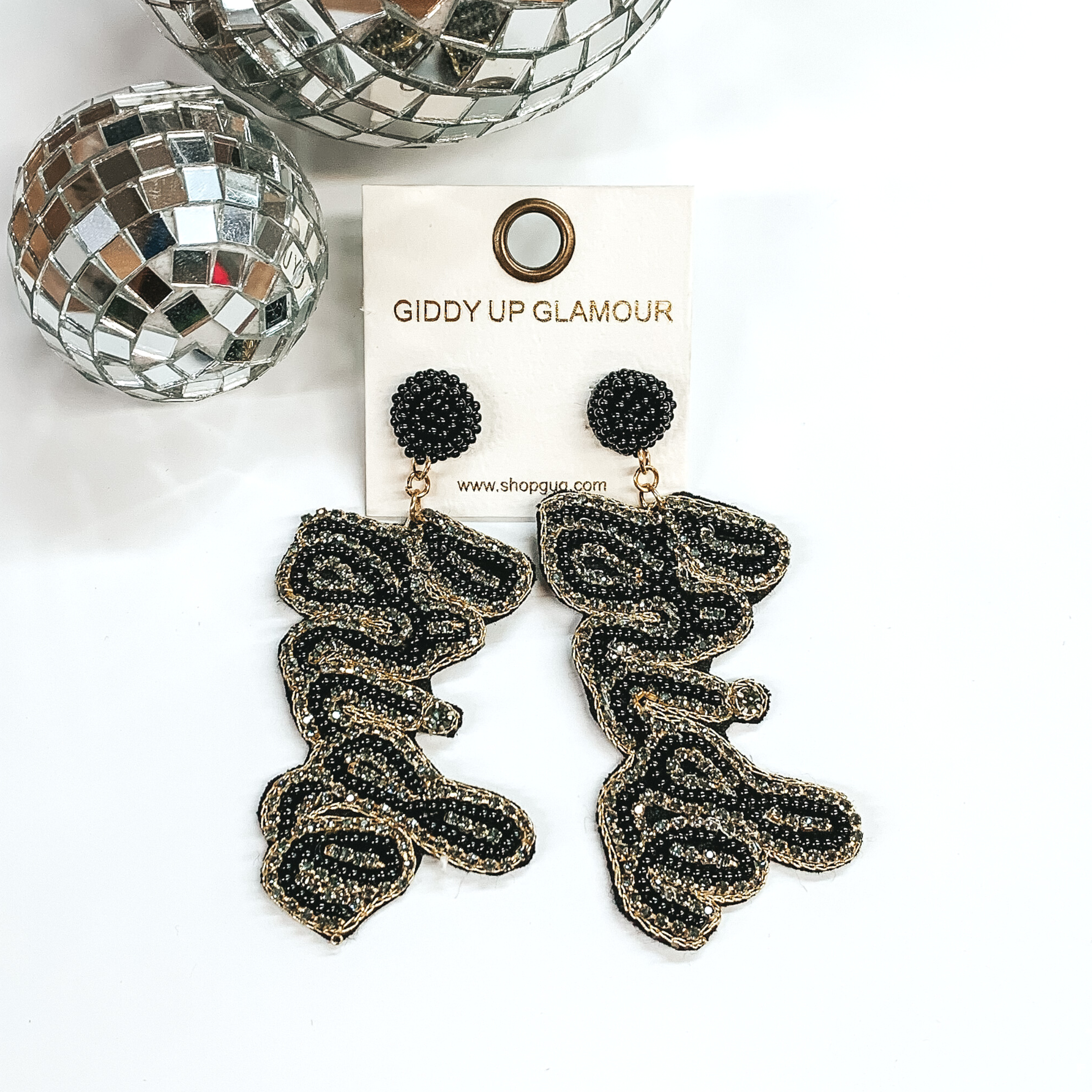 Black circle beaded stud earrings with hanging black beaded pendant that says "bride" that is surrounded by grey crystals. These earrings are pictured on a white background with disco balls in the top left corner. 