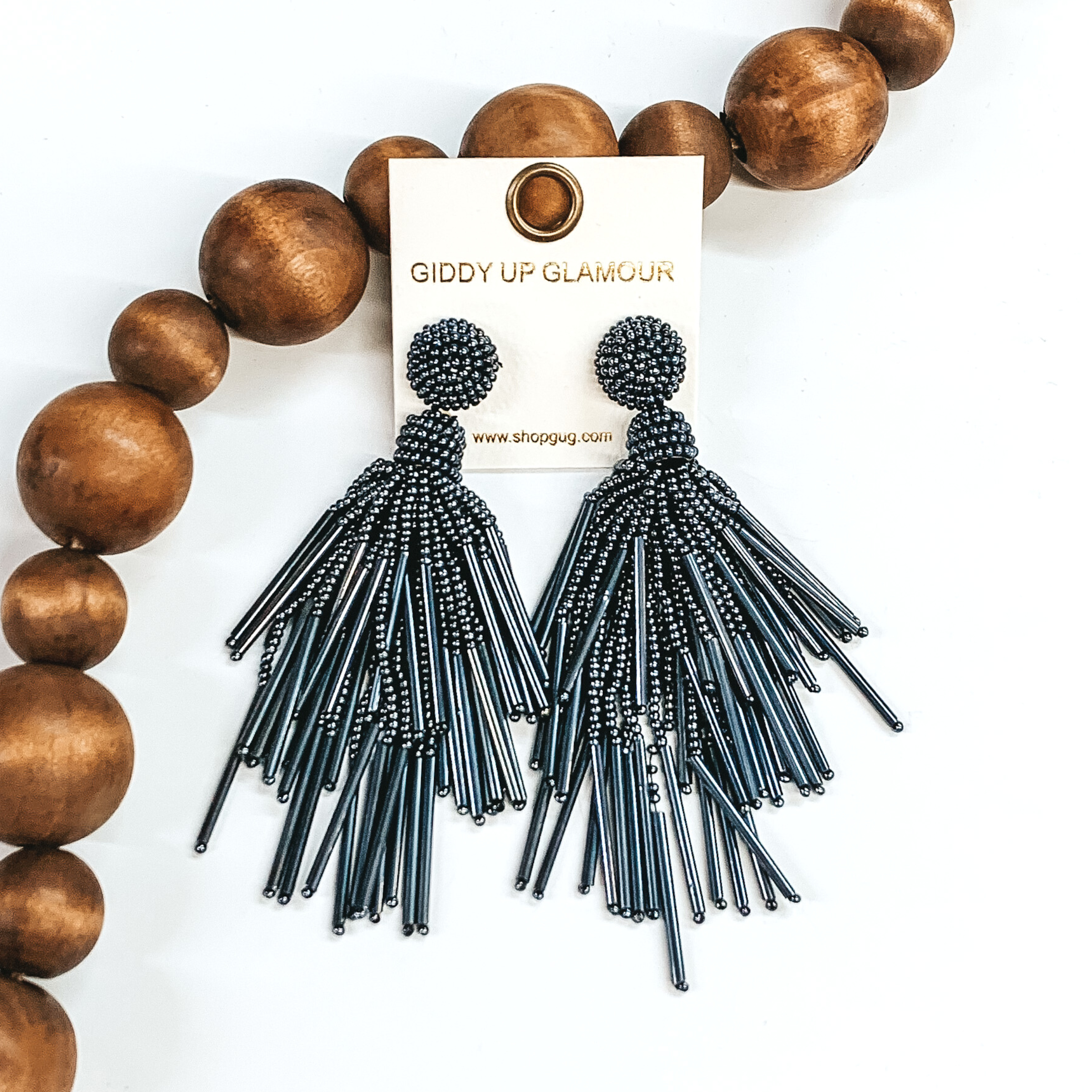 Circle beaded stud earrings with a beaded tassel in hema. These earrings are pictured on a white background with brown beads behind them.