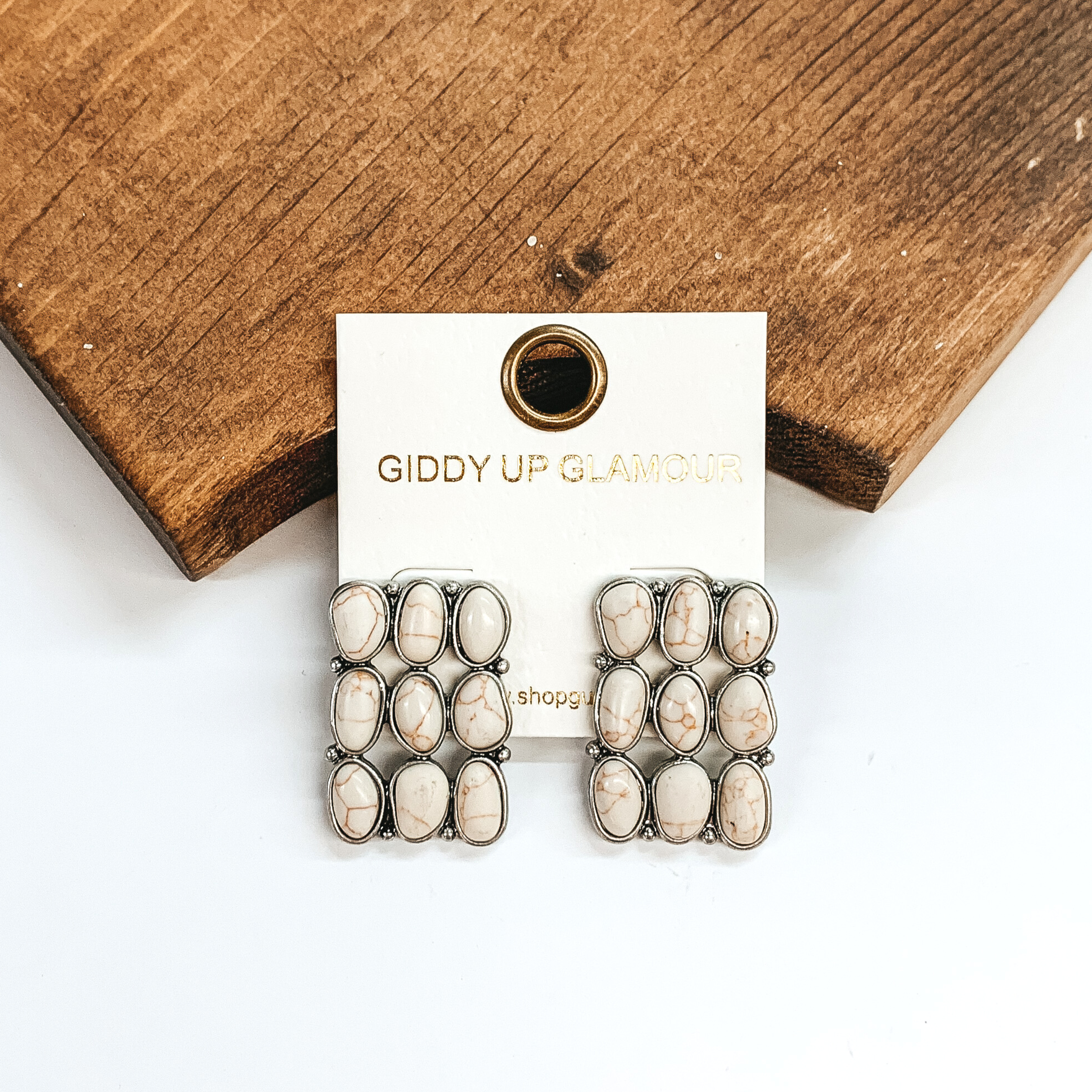 Nine ivory stone rectangle earrings. These earrings are pictured leaning against a brown block on a white background.