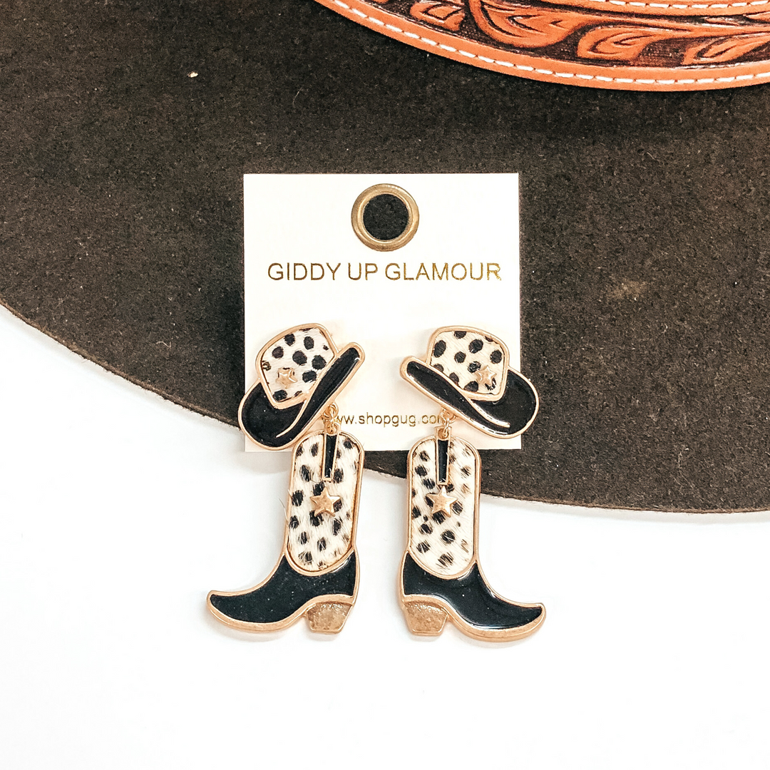 Hat stud earrings with a boot pendant drop. Both have a white and black dotted print with black on the hat brim and on the foot part on the sock. These earrings are pictured on a white and brown background. 