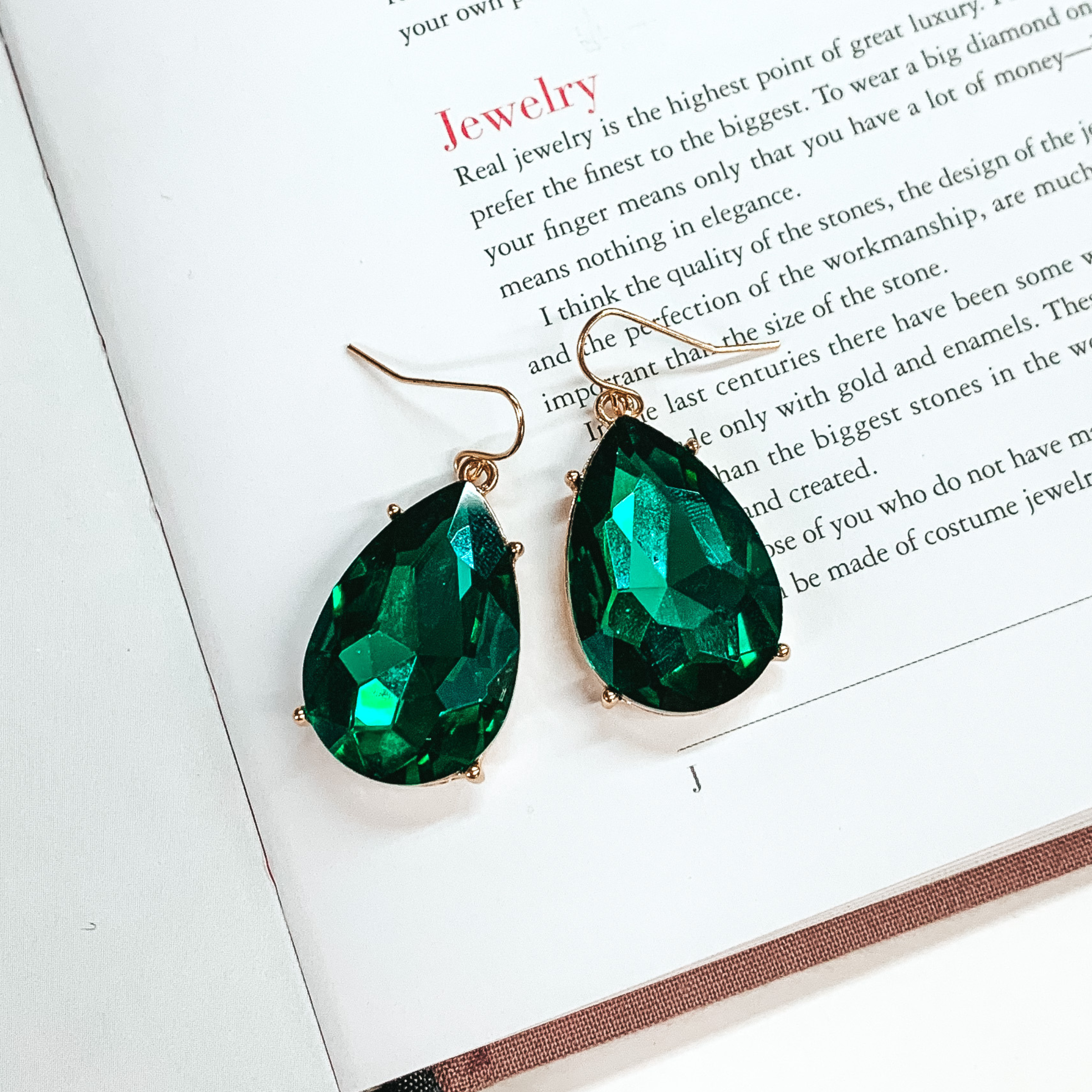 Gold fish hook earrings with large teardrop emerald crystal pendants. 