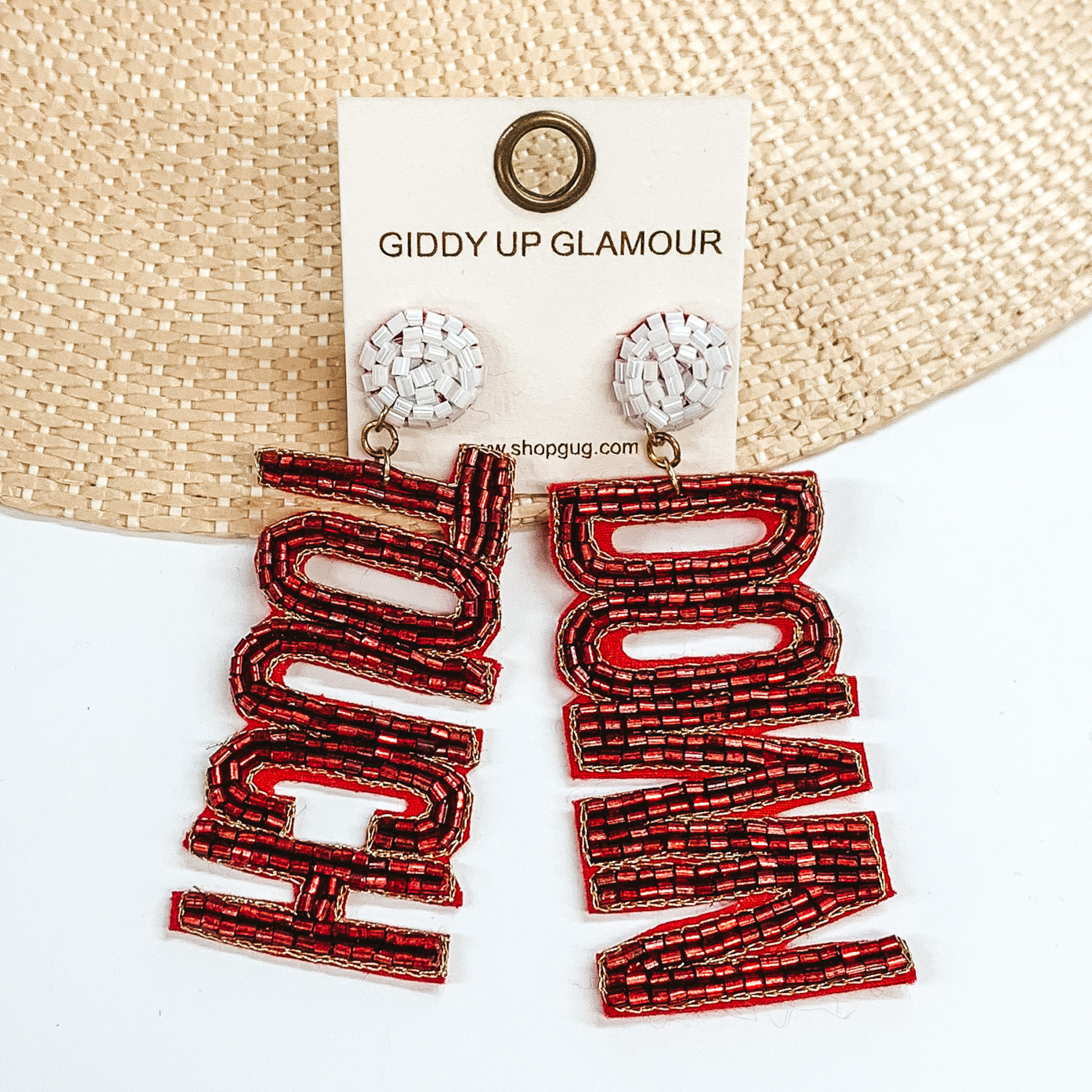 White beaded circle post back earrings. These earrings include the words "Touch" and "Down" in burgundy beads. These earrings are pictured partially laying on a straw hat brim on a white background. 