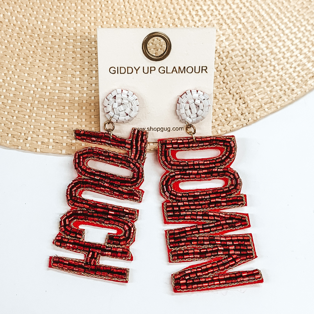 White beaded circle post back earrings. These earrings include the words "Touch" and "Down" in burgundy beads. These earrings are pictured partially laying on a straw hat brim on a white background. 