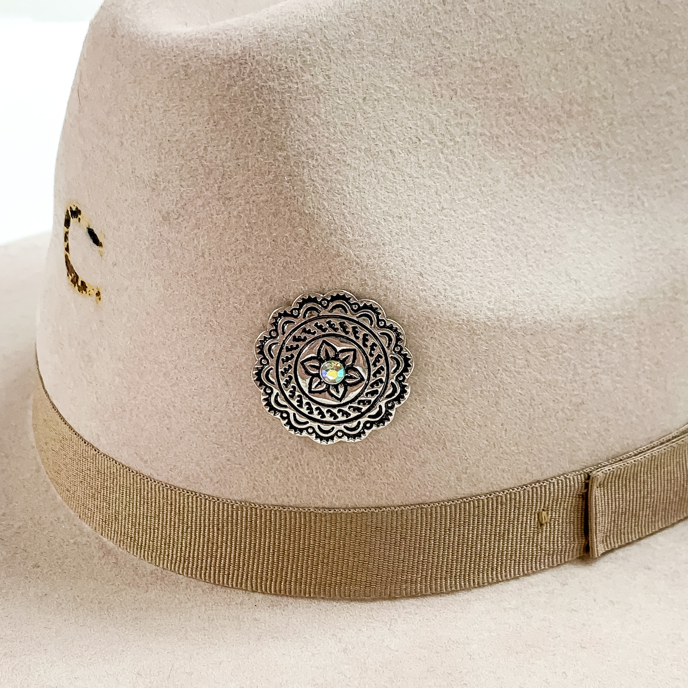 Circle concho hat pin in silver with a center ab crystal pictured on a beige colored hat pictured on a white background.