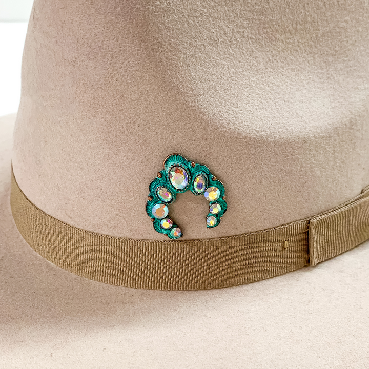 Patina naja hat pin with ab crystals pictured on a beige colored hat pictured on a white background.