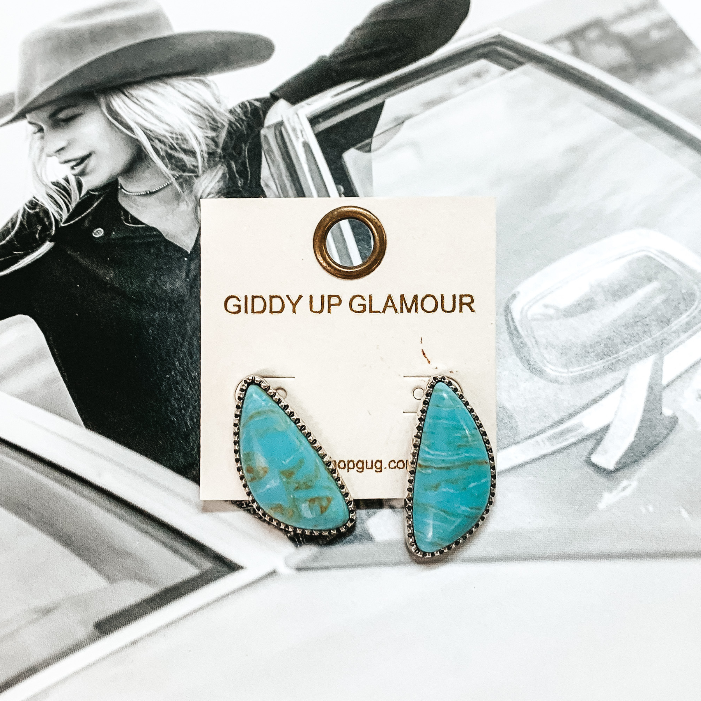 Irregular shaped turquoise stone stud earrings with a silver backing. These earrings are pictured on top of a black and white picture of a girl in a car. 