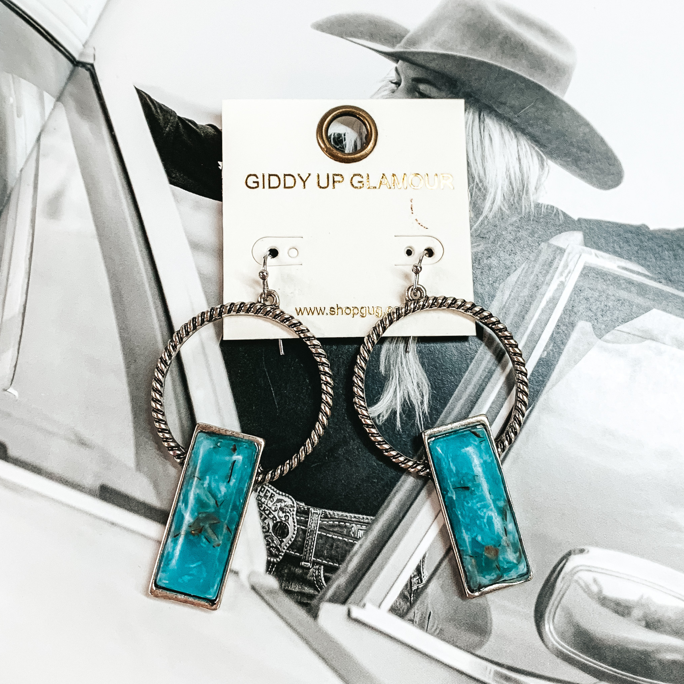 Silver hoop earrings with a rectangle faux turquoise stones. These earrings are pictured on a white and black picture. 