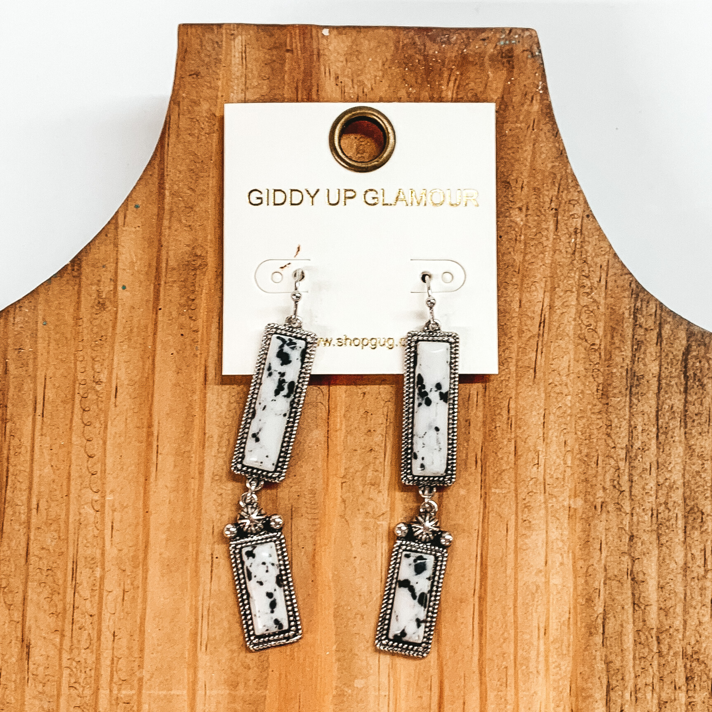 Silver drop earrings with two silver, rectangle drop. These earrings also include faux white stones. These earrings are pictured on a white and black picture. 