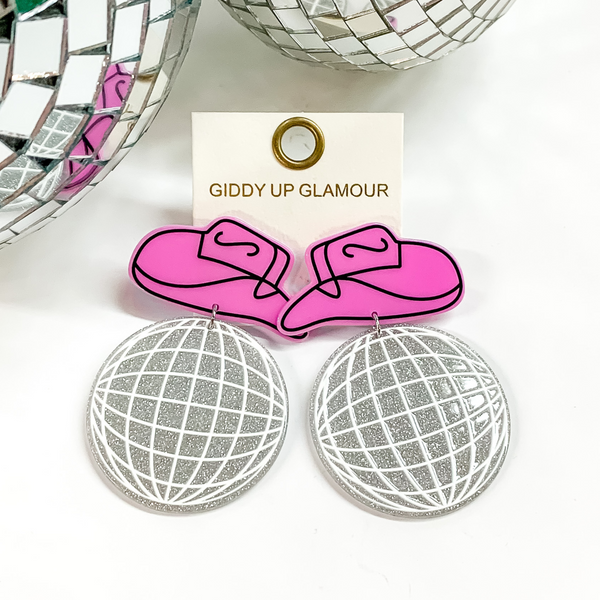 Pink cowboy hat earrings with a silver glitter and white disco ball pendant. These earrings are pictured on a white background with disco balls at the top.