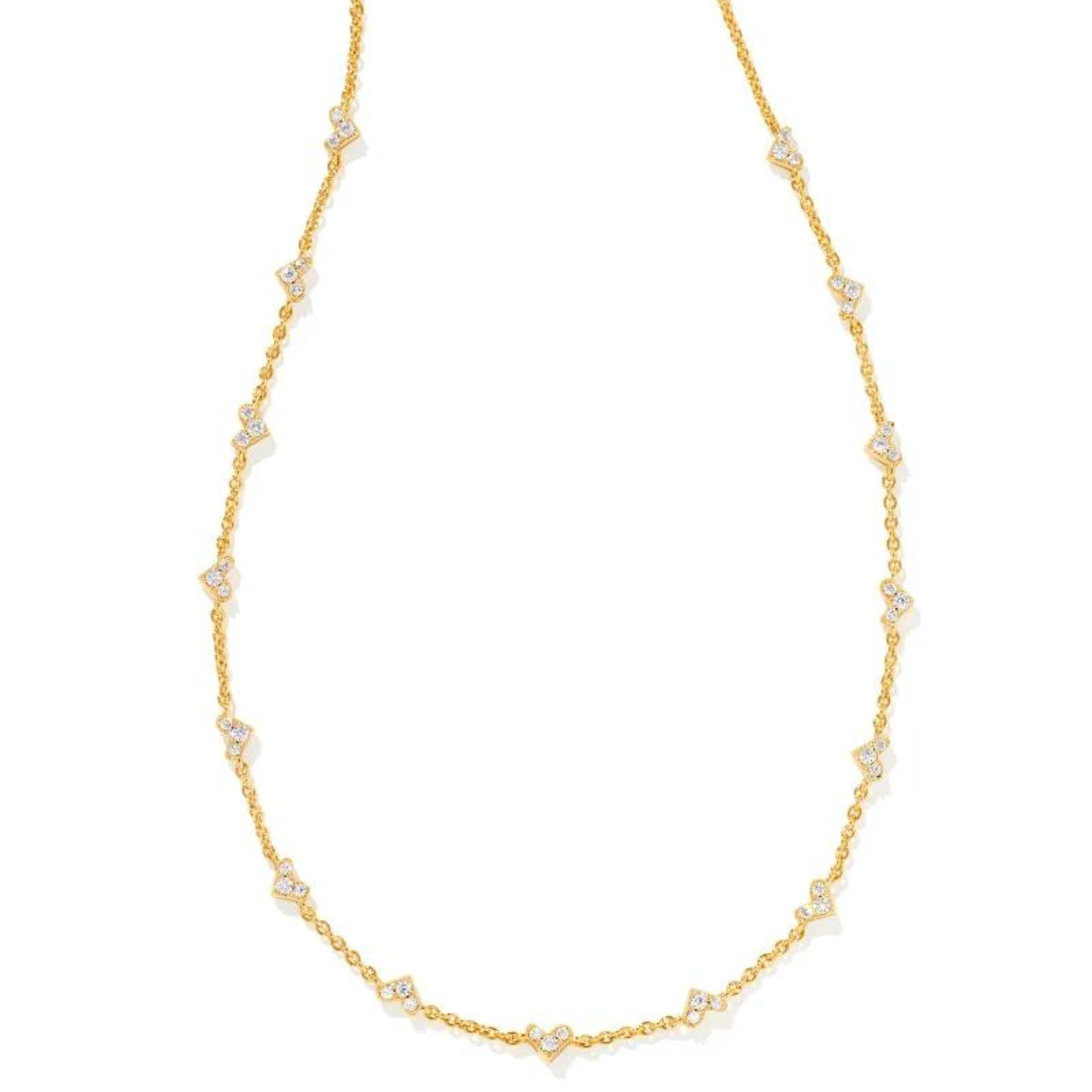 Thin, gold chain necklace with small, heart clear crystal pendants pictured on a white background. 
