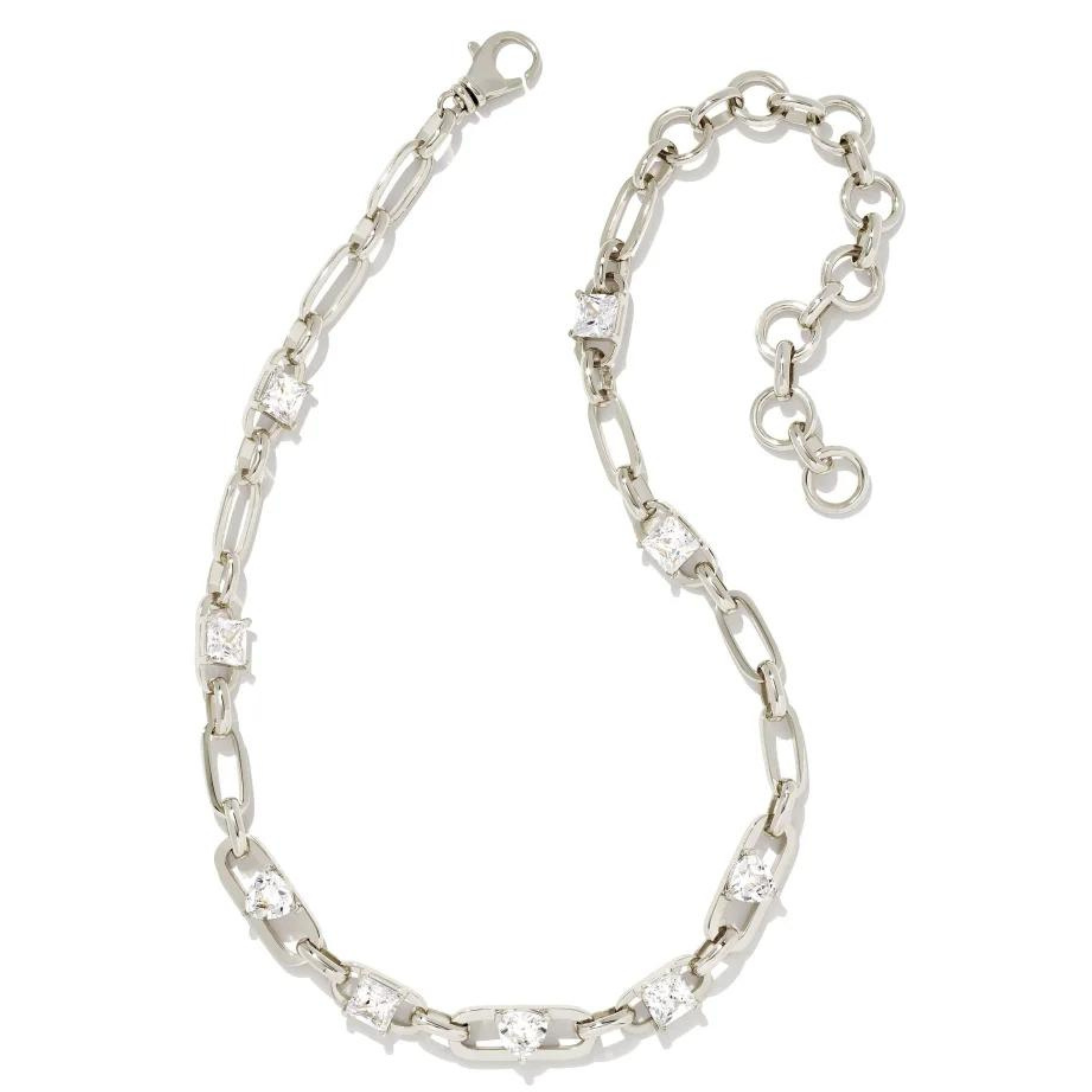 Silver chain necklace with different shaped clear crystals throughout the necklace. This necklace is pictured on a white background. 