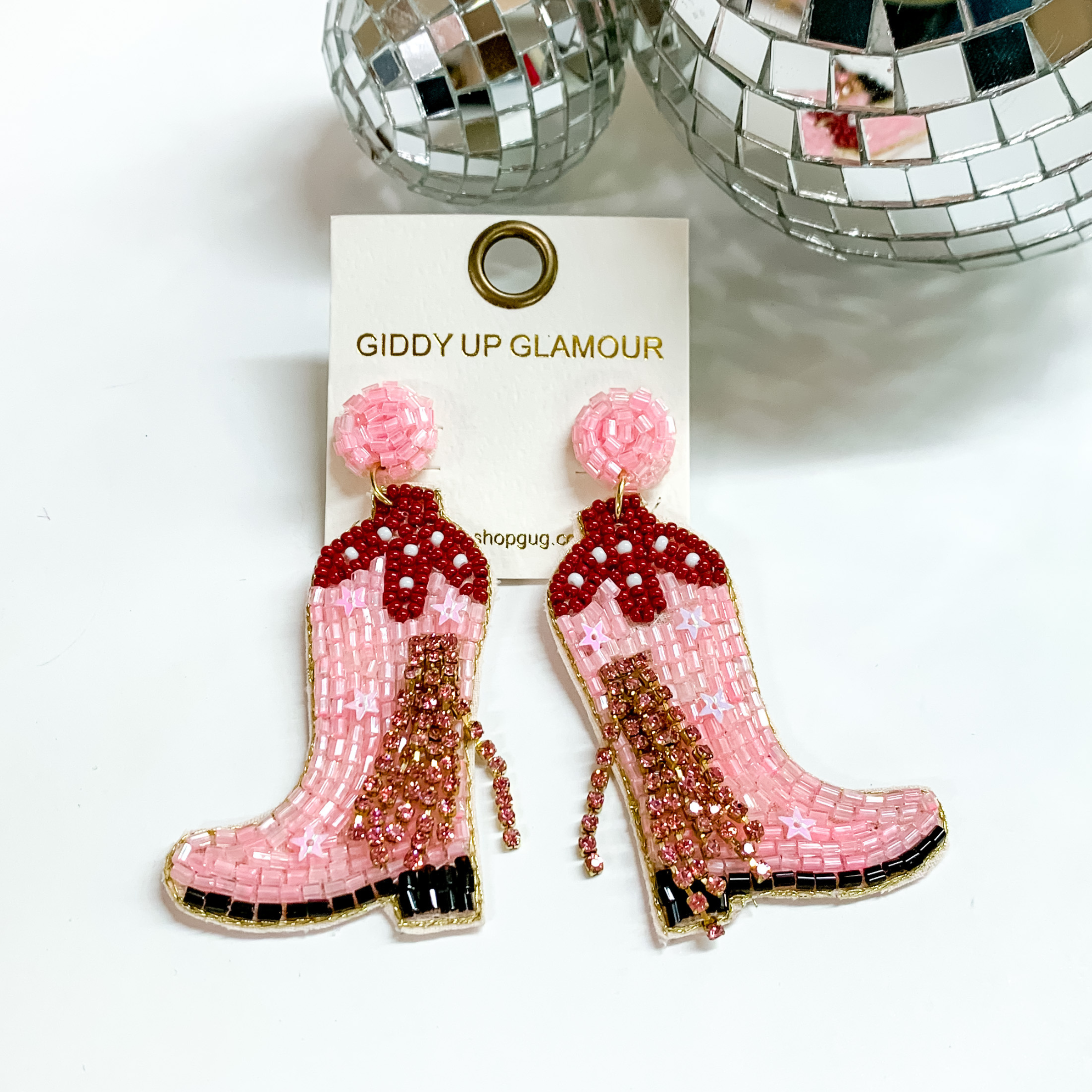 Pink beaded boot earrings with pink crystal tassels. These beaded earrings also include a dark pink top, black sole, and pink sequin stars throughout. These earrings are pictured on a white background with disco balls at the top.