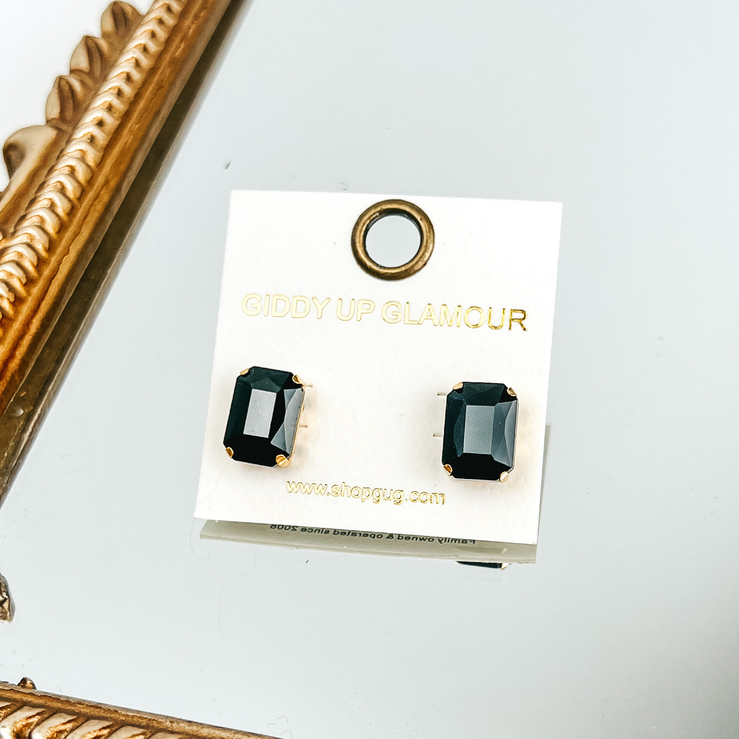 Black, rectangle crystal earrings on a white earrings holder. This bracelet is pictured laying on a gold mirror on a white background. 