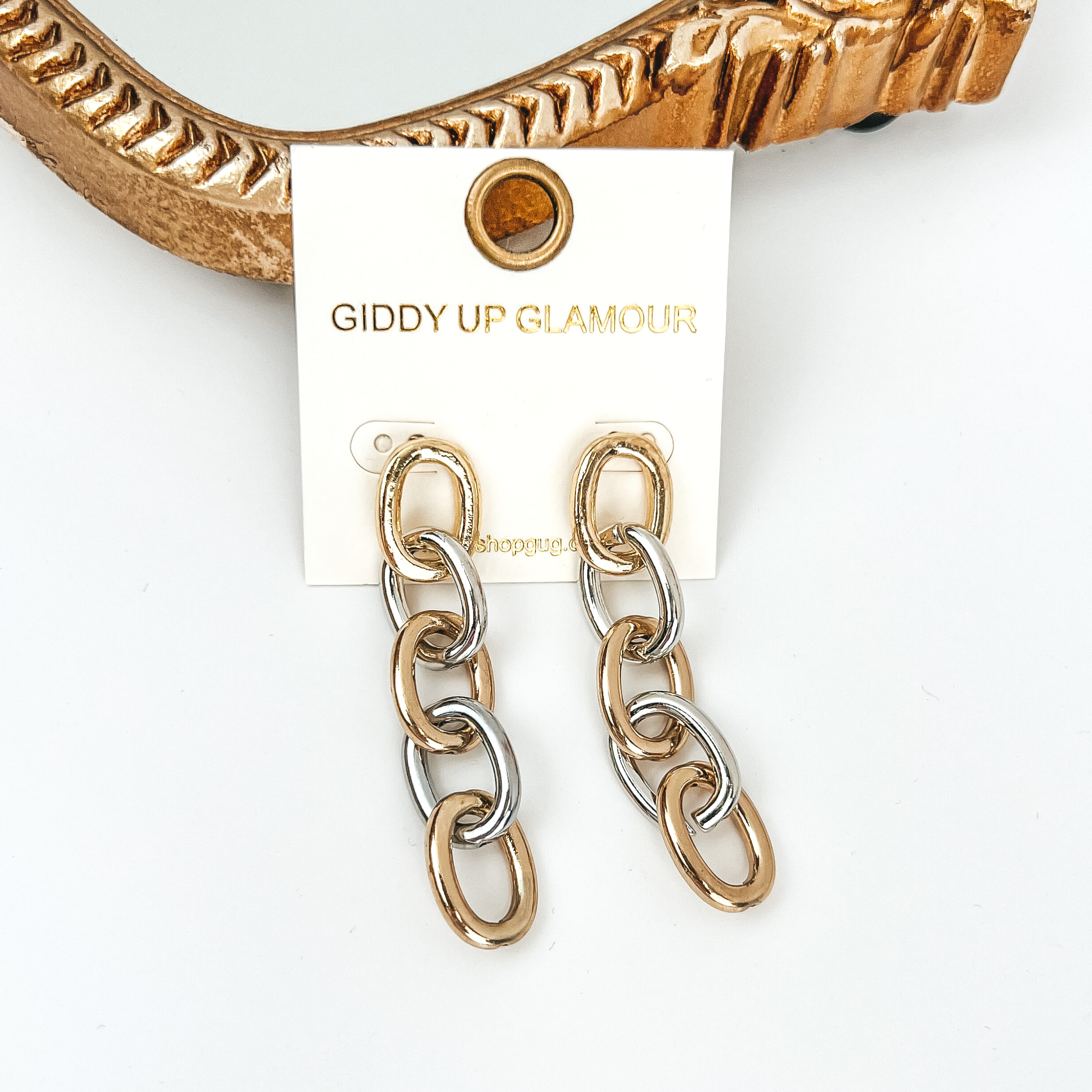 Gold and silver chain link drop earrings. These earrings are pictured on a white background with a gold mirror at the top of the picture. 