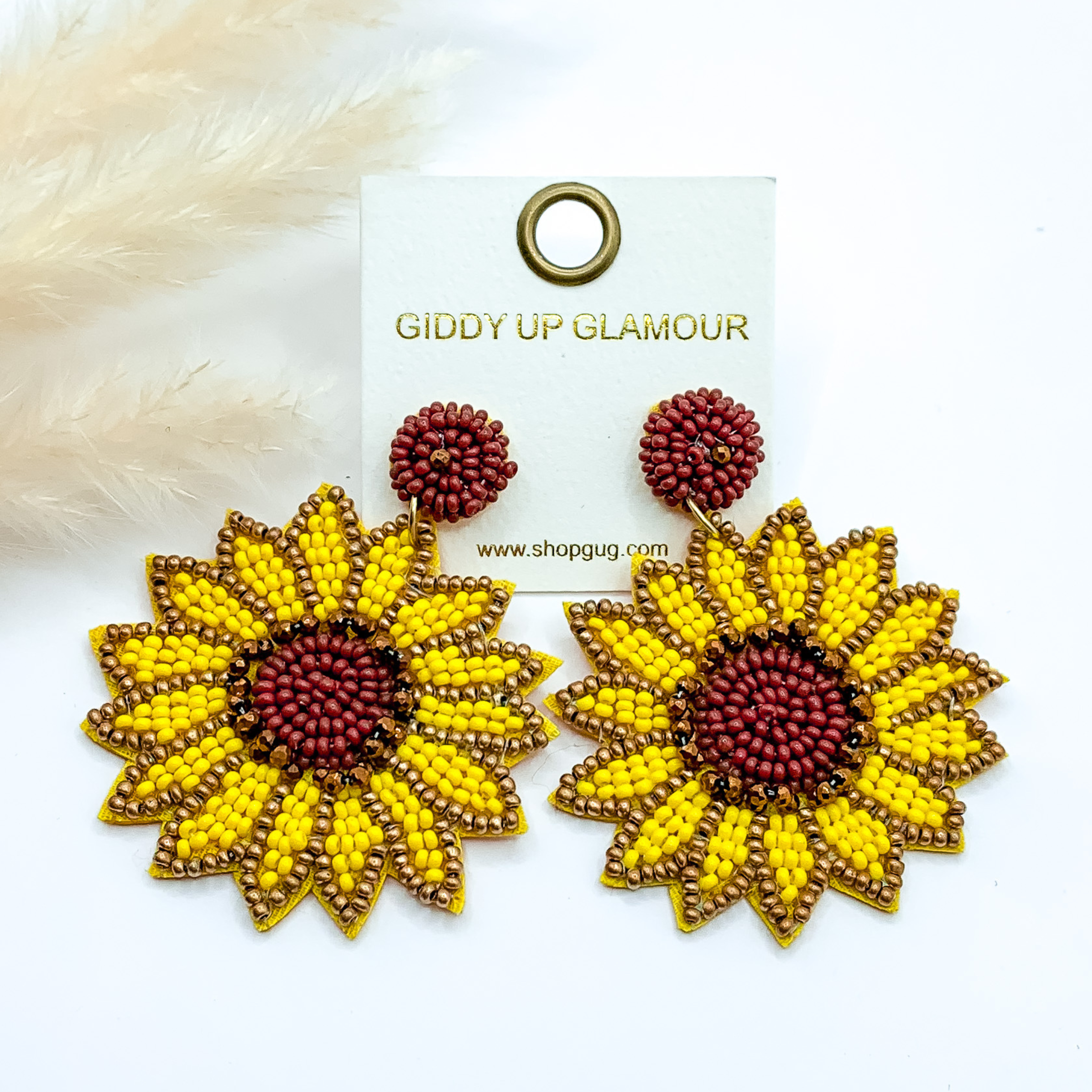 Beaded sunflower drop earrings. These earrings include yellow, gold, and brown beads. These earrings are pictured on a white background. 