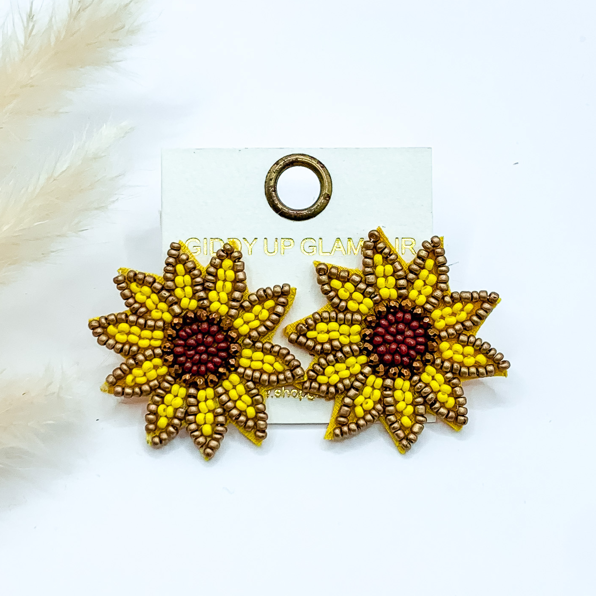 Beaded sunflower stud earrings. These earrings include yellow, gold, and brown beads. These earrings are pictured on a white background. 