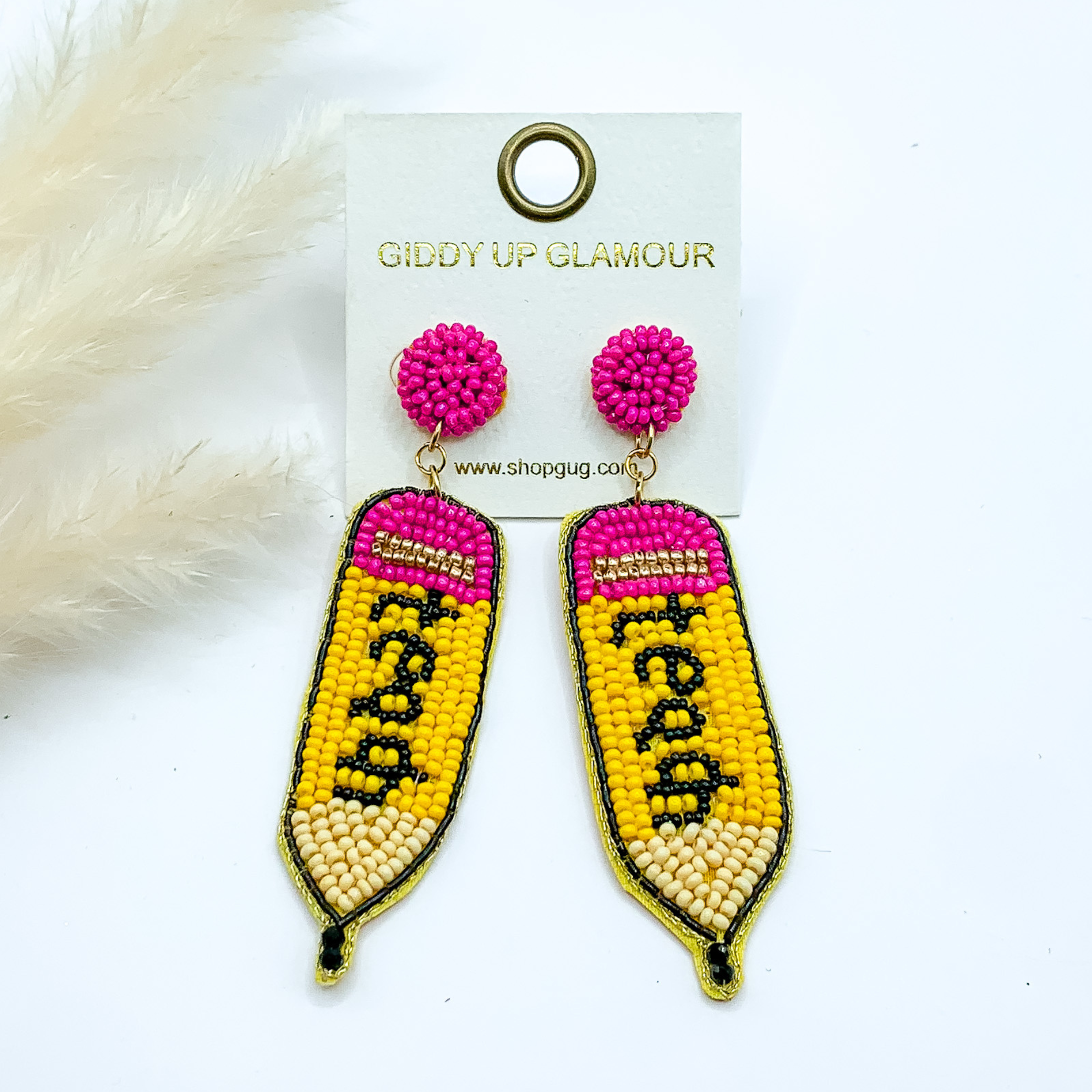 Pink beaded circle post earrings with a beaded pencil pendant. This pendant includes the colors of a pencil and the word "teach" is spelled out in black beads. These earrings are pictured on a white background. 