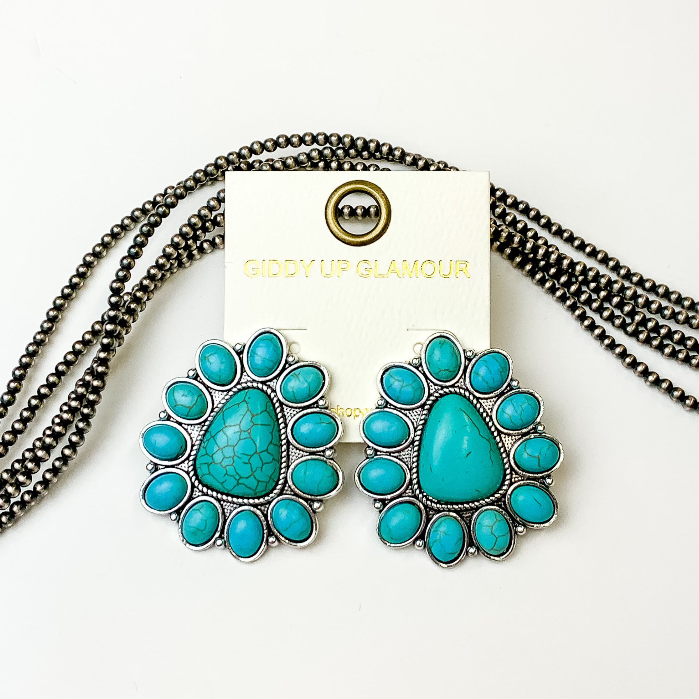Triangular turquoise stone cluster earrings. These earrings are pictured on a white background with silver beads behind the earrings. 
