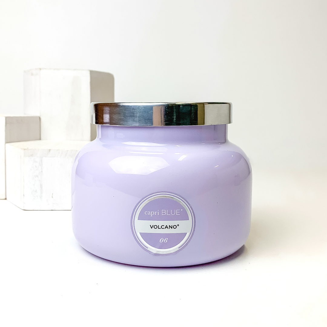 Light lavender candle with a silver lid. This candle is pictured on a white background with white blocks on the left side of the candle. 