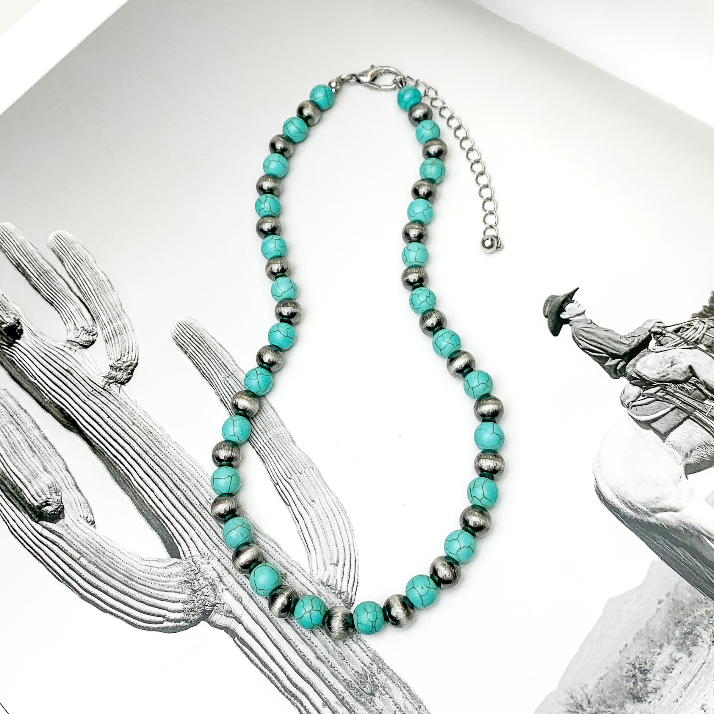 Silver and turquoise beaded necklace. This necklace is pictured on an open black and white western picture book. 