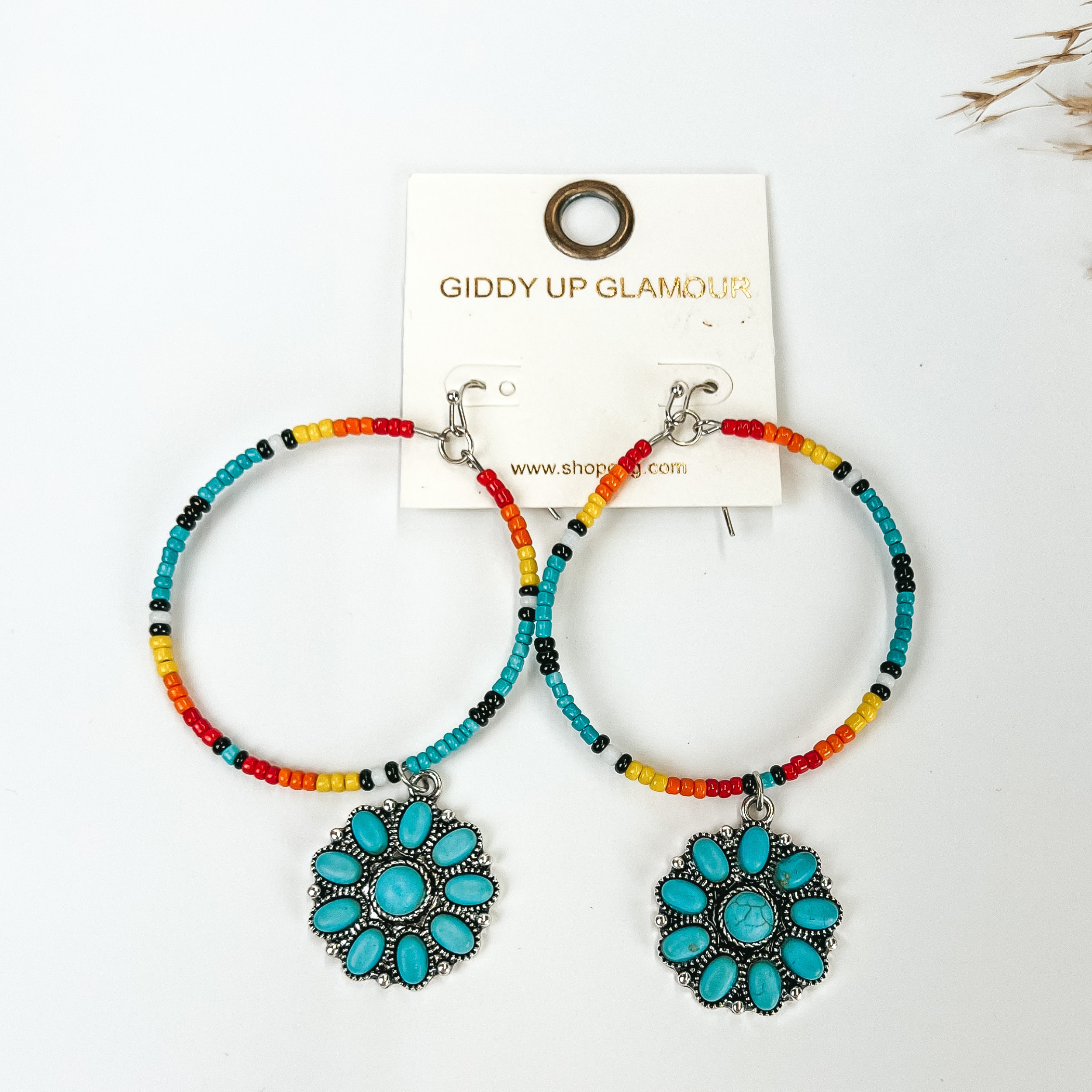 Multicolored Seed Beaded Circle Drop Earrings with Turquoise cluster Pendant pictured with pampas grass, on a white background. 