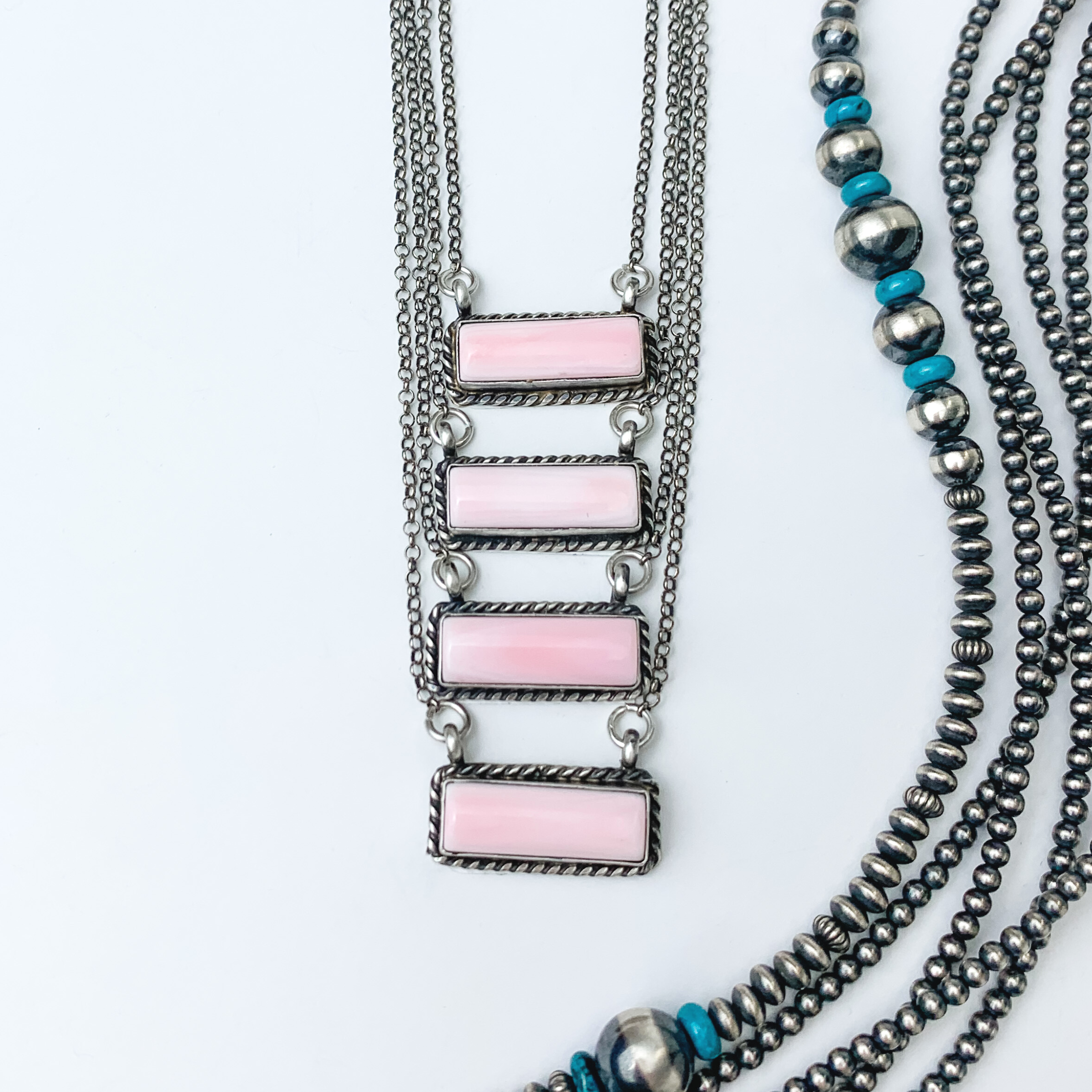 Pictured are four pink conch rectangle bar necklaces. These necklaces include a silver outline and silver chain necklace. These necklaces are pictured on a white background with silver beads on the right side of the picture. 