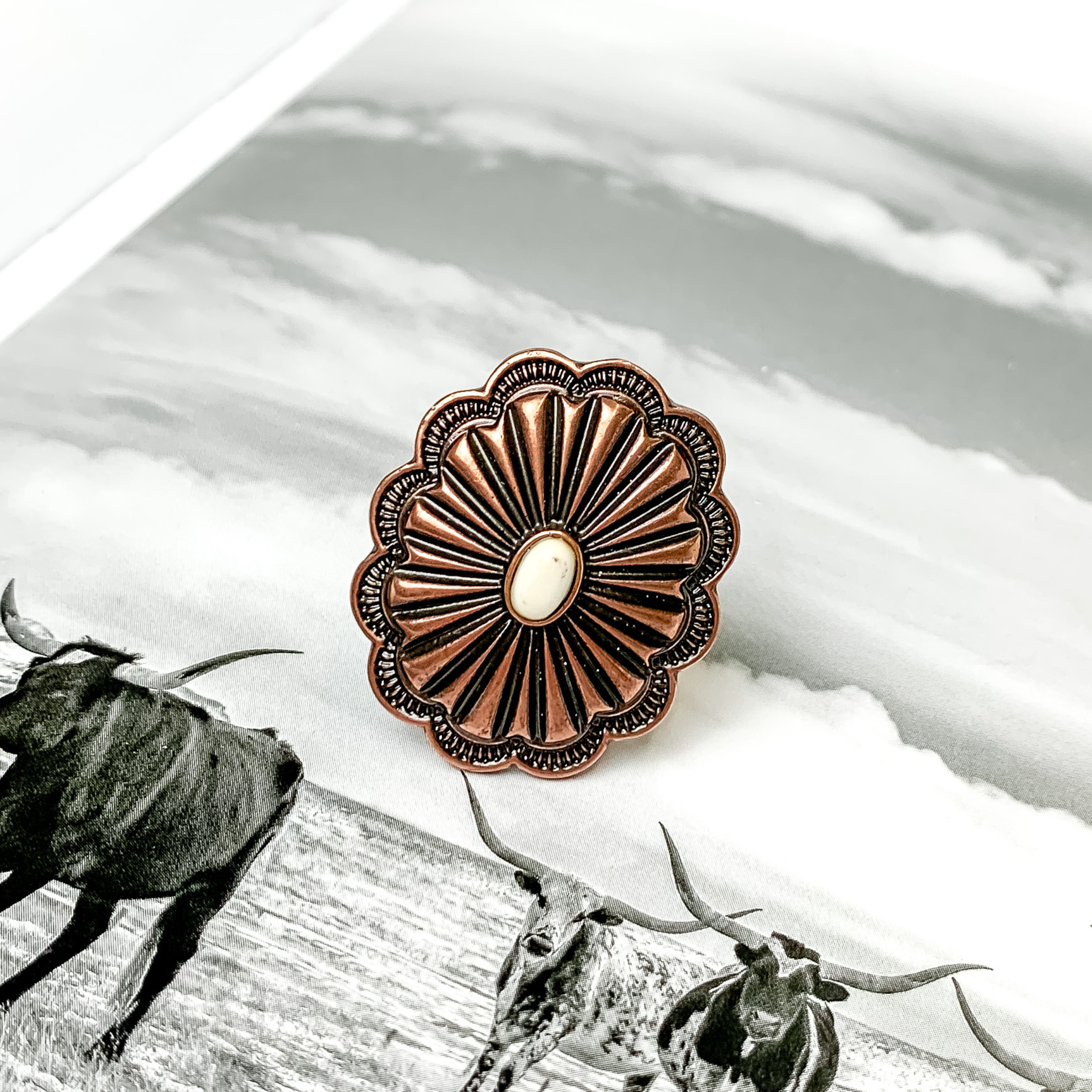 Copper concho oval ring with a small, center ivory stone. This ring is pictured on a black and white picture. 