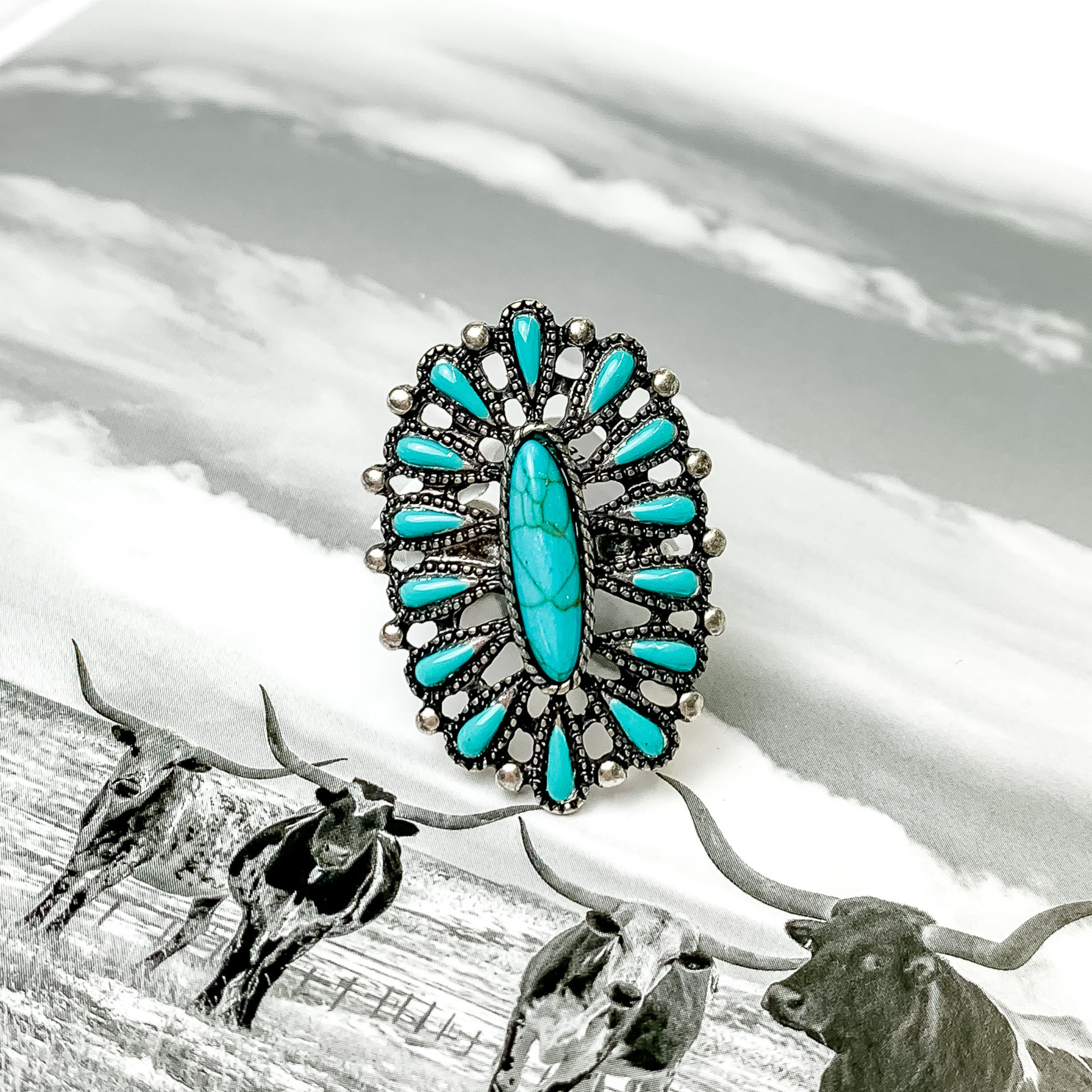 Oval turquoise cluster ring ring in silver. This ring is pictured on a black and white picture. 