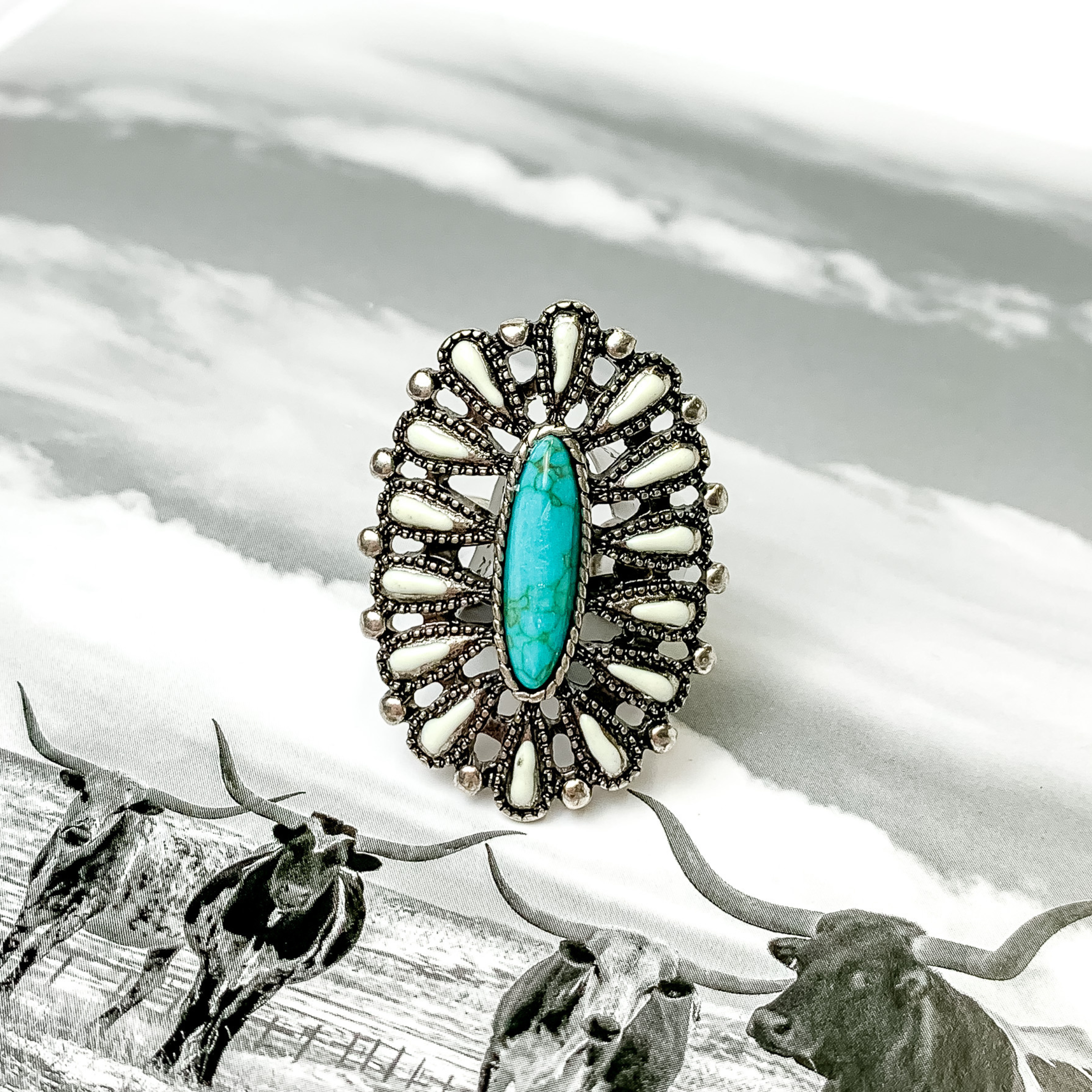 Oval ivory and turquoise cluster ring in silver. This ring is pictured on a black and white picture. 