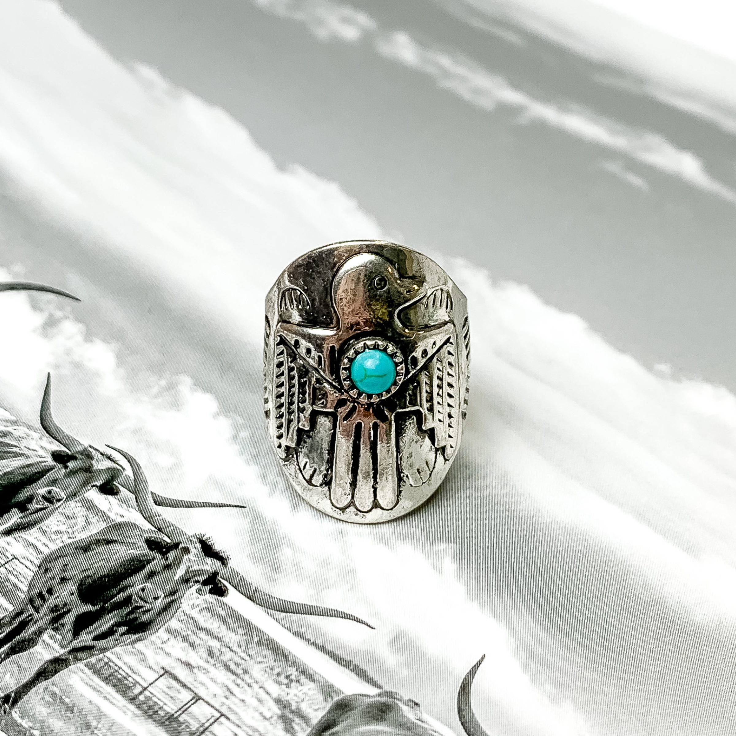 Silver thunderbird ring with small turquoise stone. This ring is pictured on a black and white picture. 