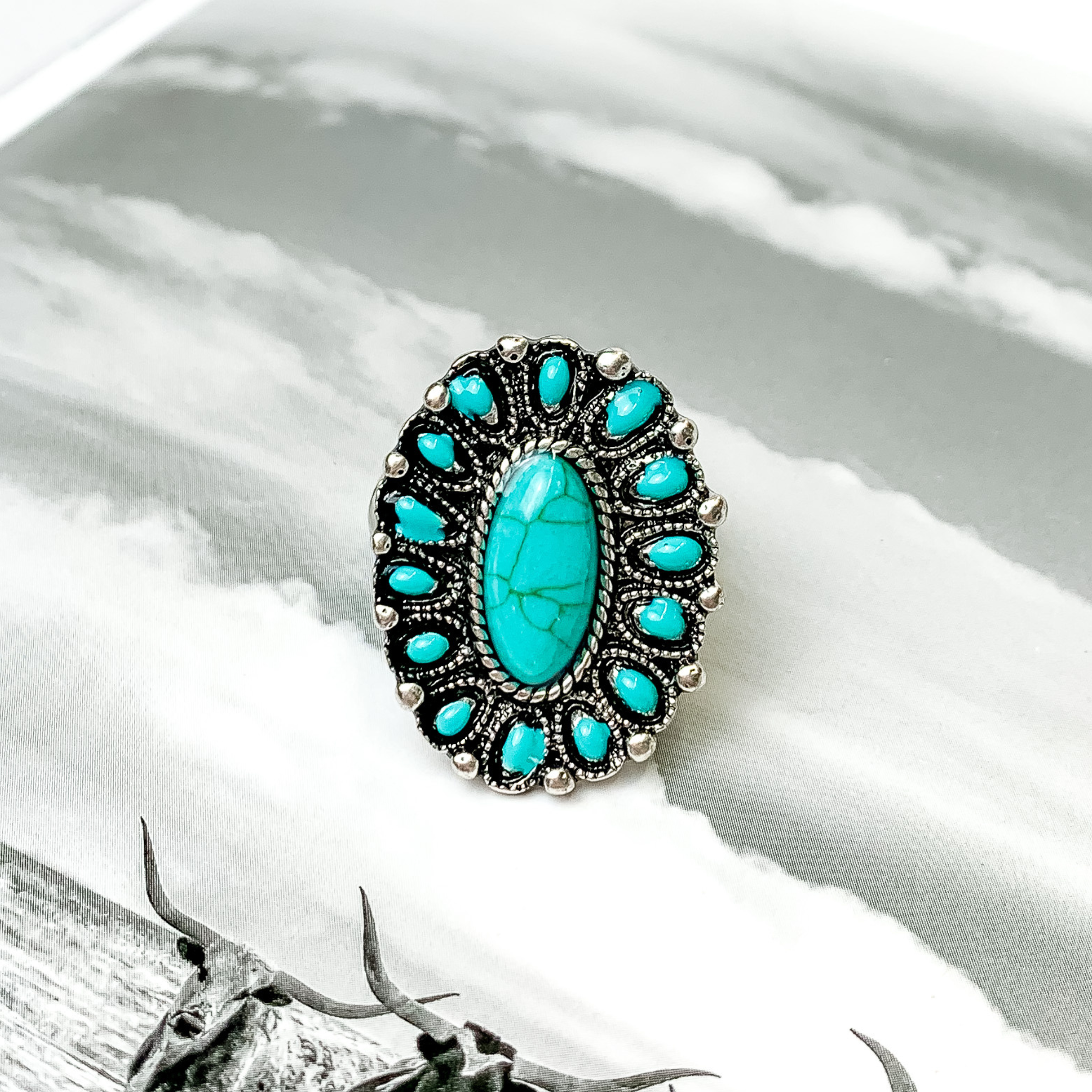 Turquoise cluster ring in silver. This ring is pictured on a black and white picture. 