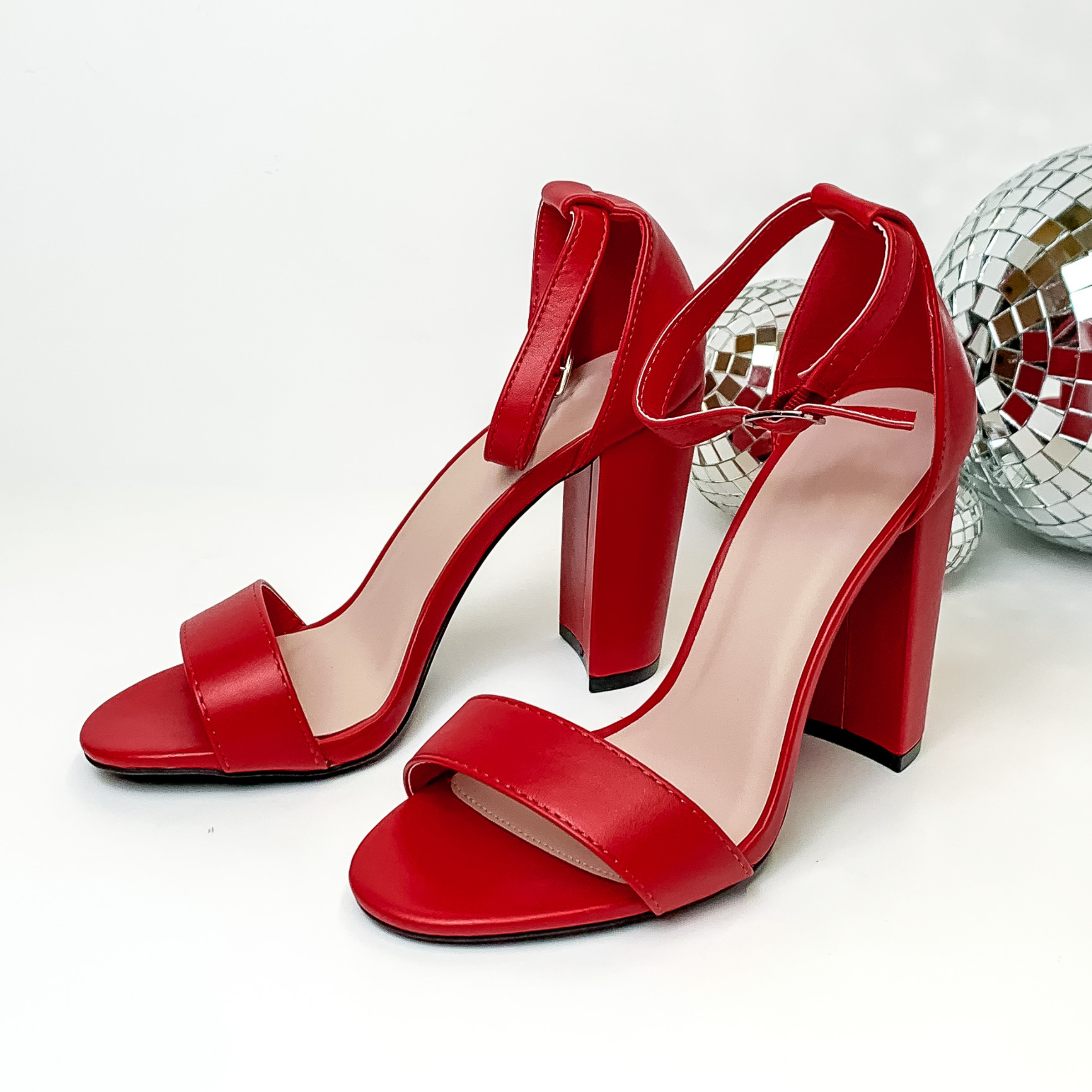 Red, block high heel sandals with an adjustable strap. These heels are pictured on a white background with disco balls on the right side of the heels. 