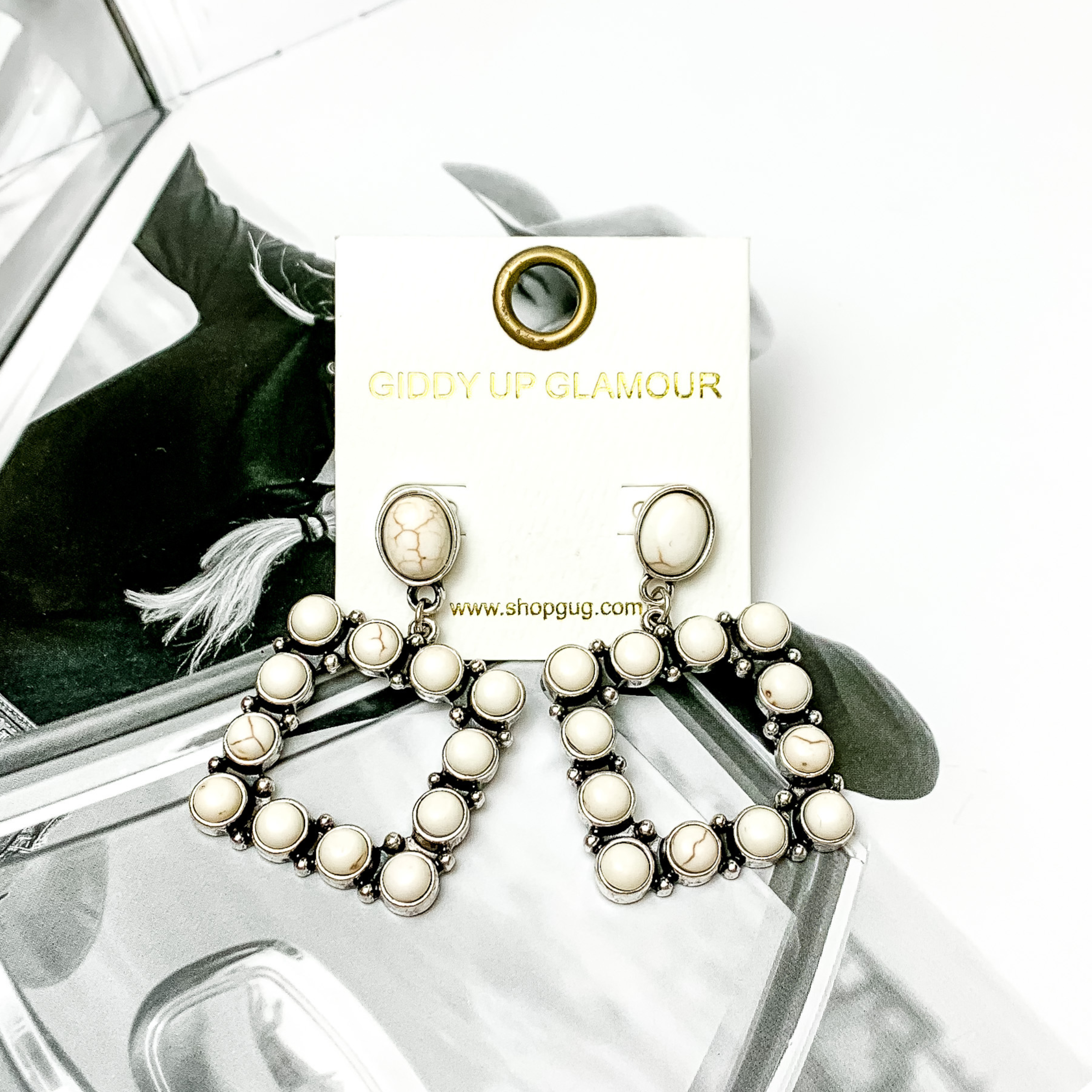 Open square drop earrings with ivory stones. These earrings are pictured on a black and white picture. 