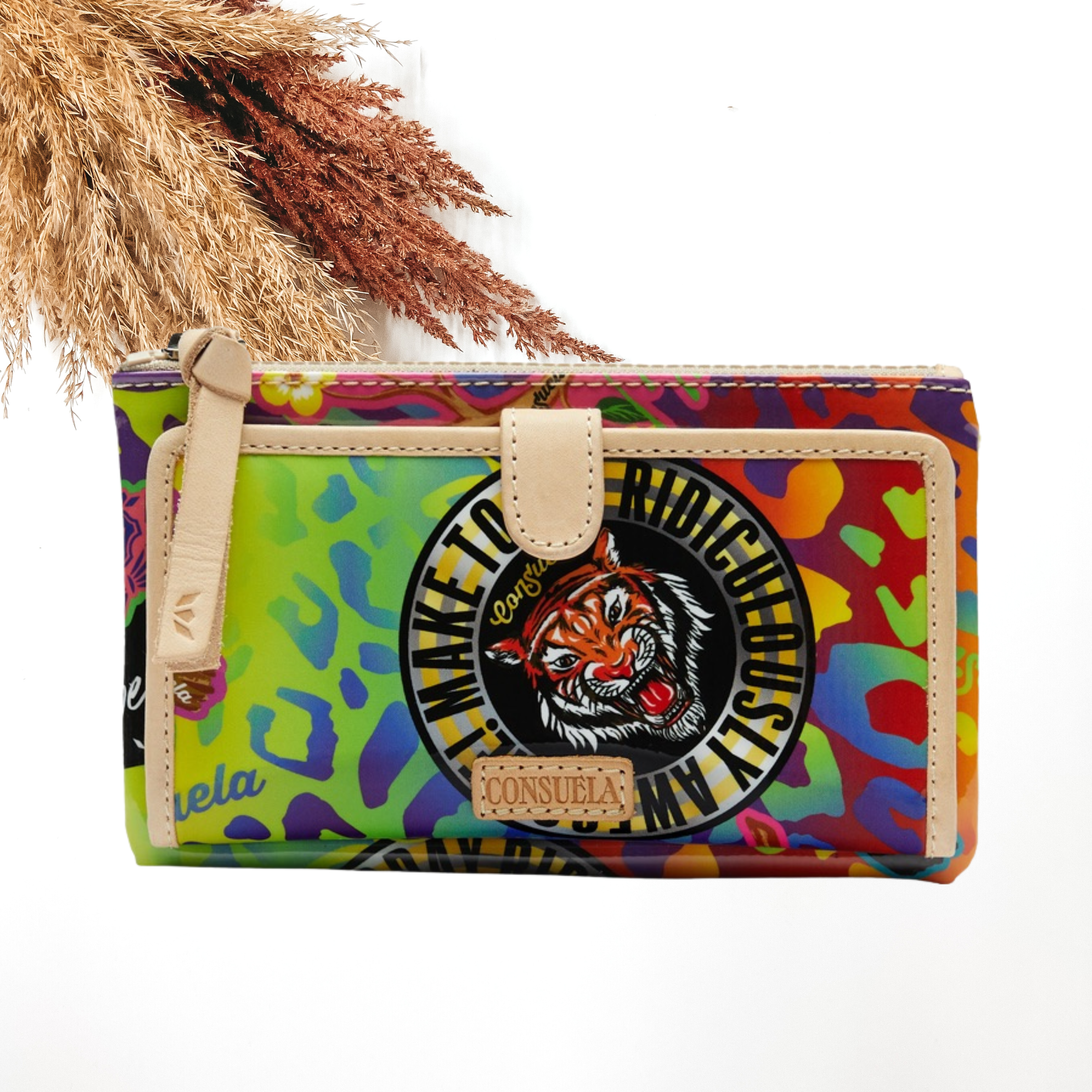 Pictured is a rectangle wallet that has a multicolored leopard print design and it includes random sticker patches throughout the wallet. This wallet includes a front flap with a light tan outline and a top zipper with a light tan zipper pull. This wallet is pictured on a white background with pompous grass in the top left corner. 