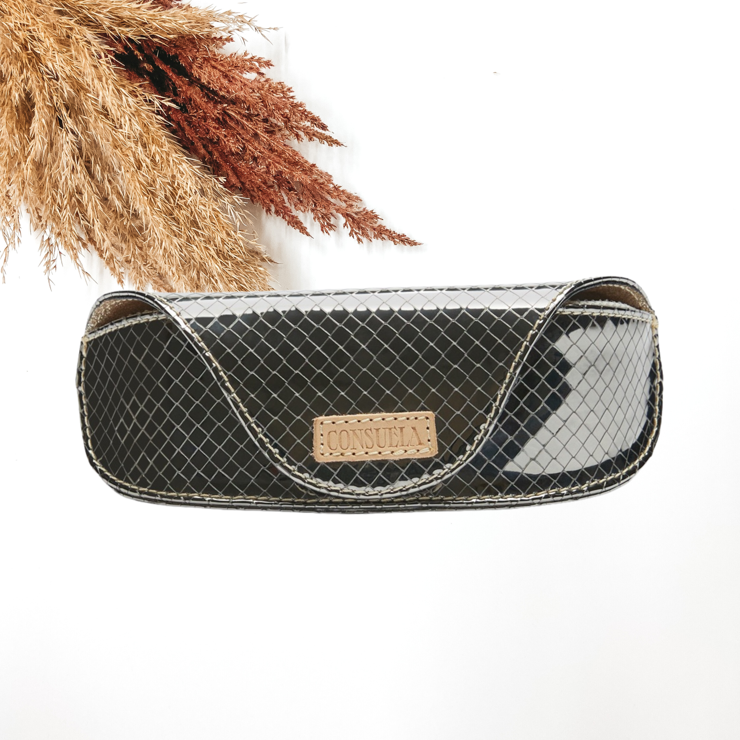 Pictured is a rectangle wallet that has a metallic silver color with a square woven pattern. This case is pictured on a white background with pompous grass in the top left corner. 